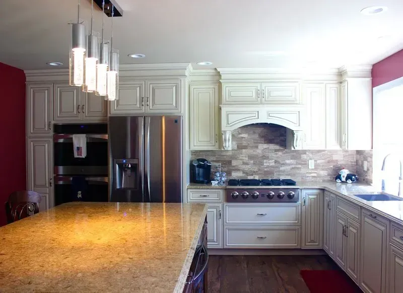 Bright modern kitchen with white cabinets, stainless steel appliances, granite island, and pendant lights  In Bucks County PA