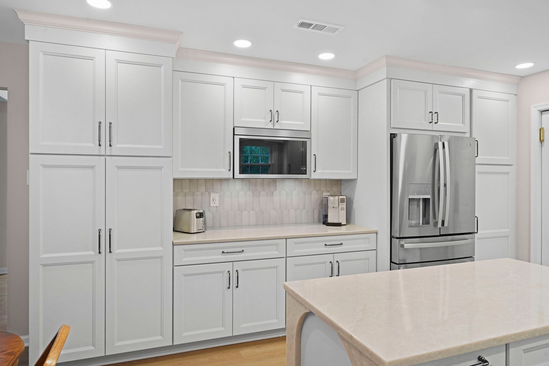 Bright white modern kitchen with stainless steel appliances and a large island counter in Langhorne