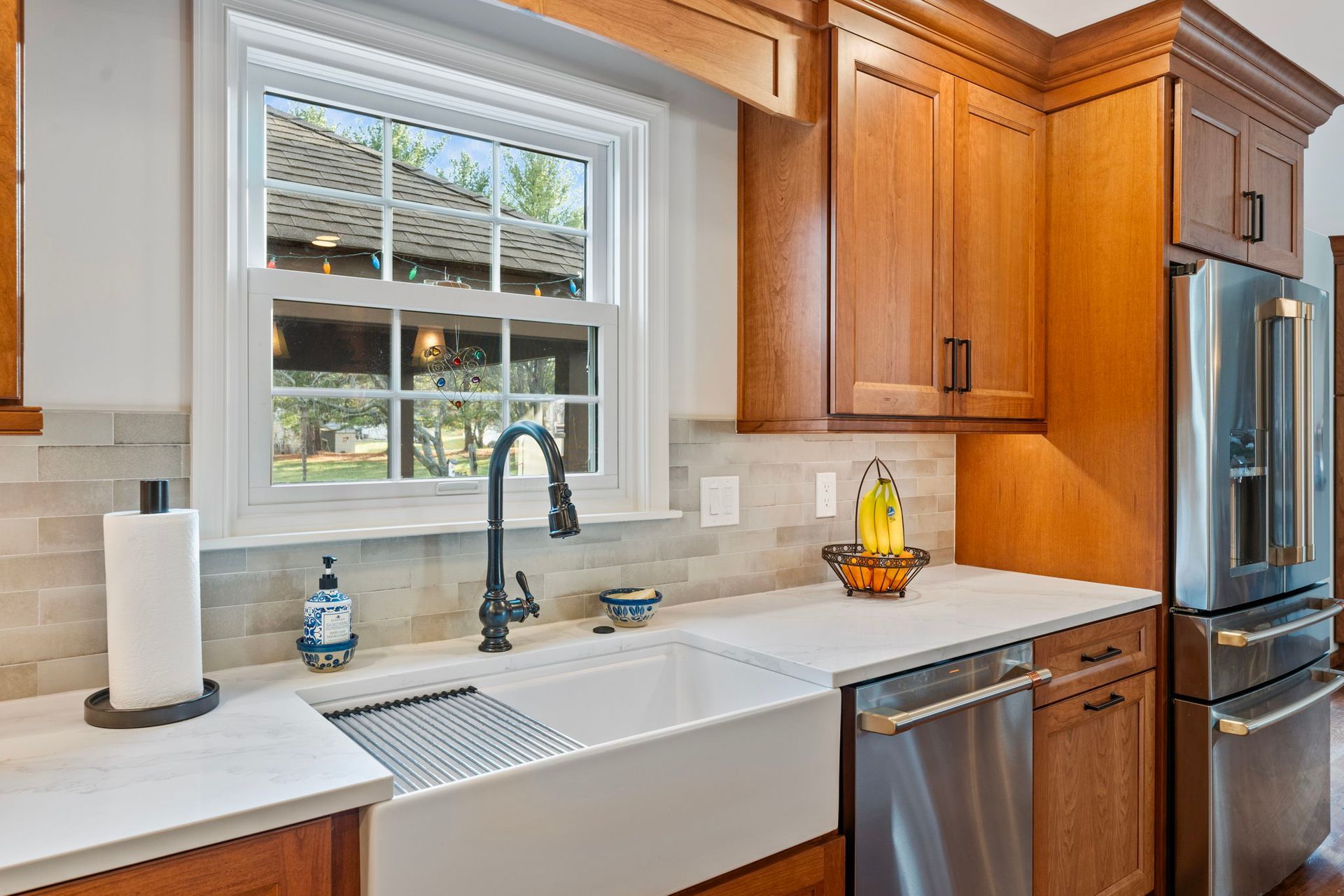 Bright kitchen sink beneath a window, with white countertops, wood cabinets, and stainless appliances In Bucks County PA