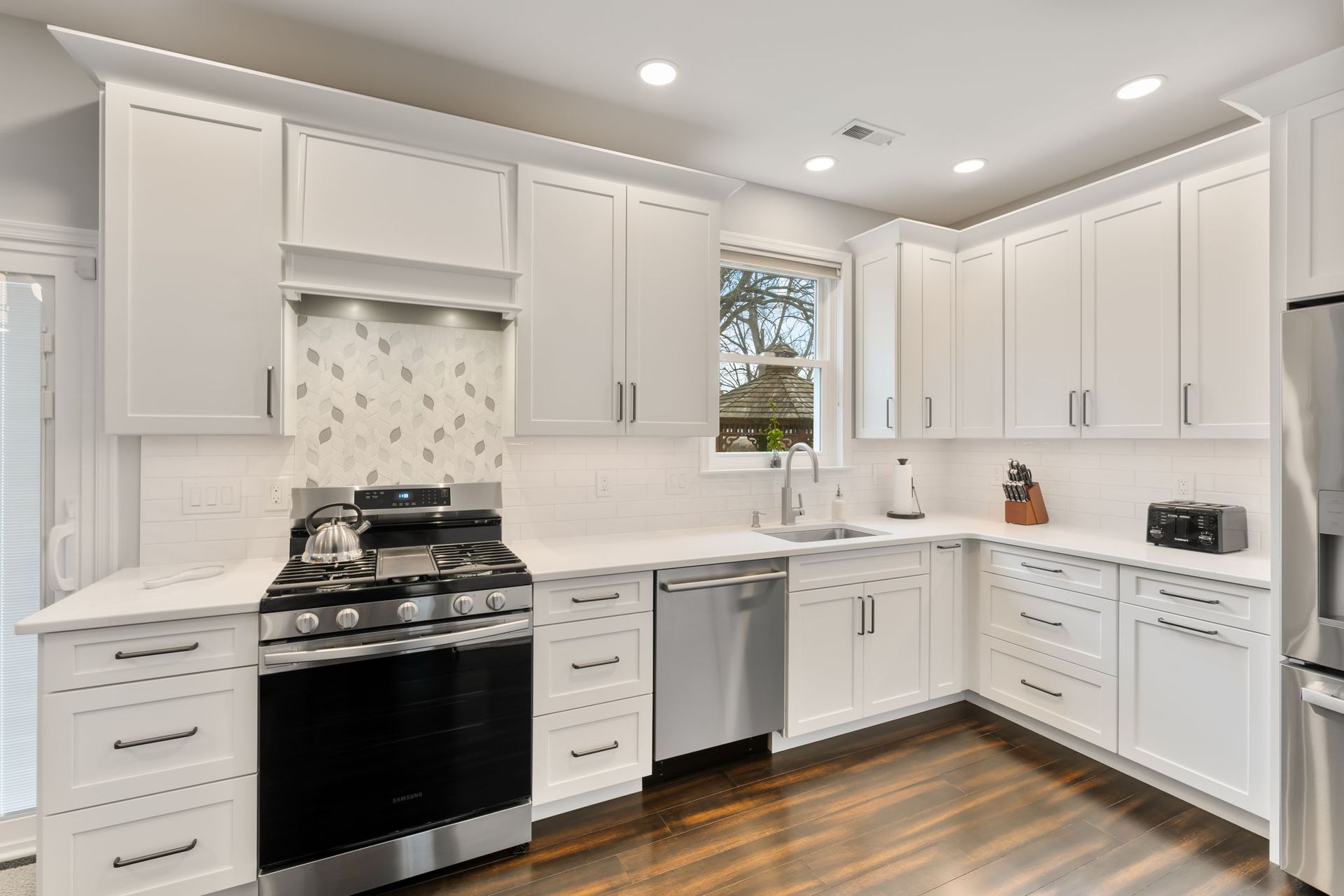 Bright white modern kitchen with stainless appliances, black stove, and wood floors  In Bucks County PA