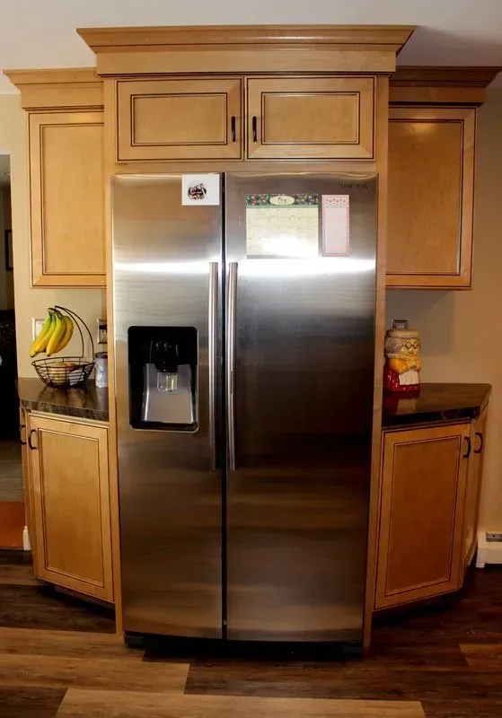 Stainless steel refrigerator built into light wood kitchen cabinetry with a black water dispenser  In Bucks County PA