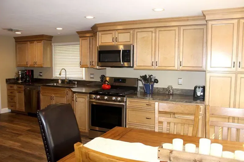 Bright kitchen with light wood cabinets, black appliances, and a wooden dining table in the foreground  In Bucks County PA