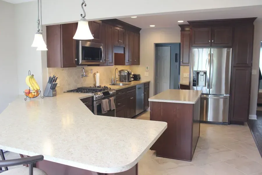 Modern kitchen with dark cabinets, stainless steel appliances, and a large light-colored island counter In Bucks Country PA