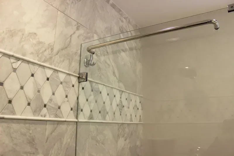 Bathroom shower with beige tile and a chrome shower rod mounted across the corner In Bucks County PA