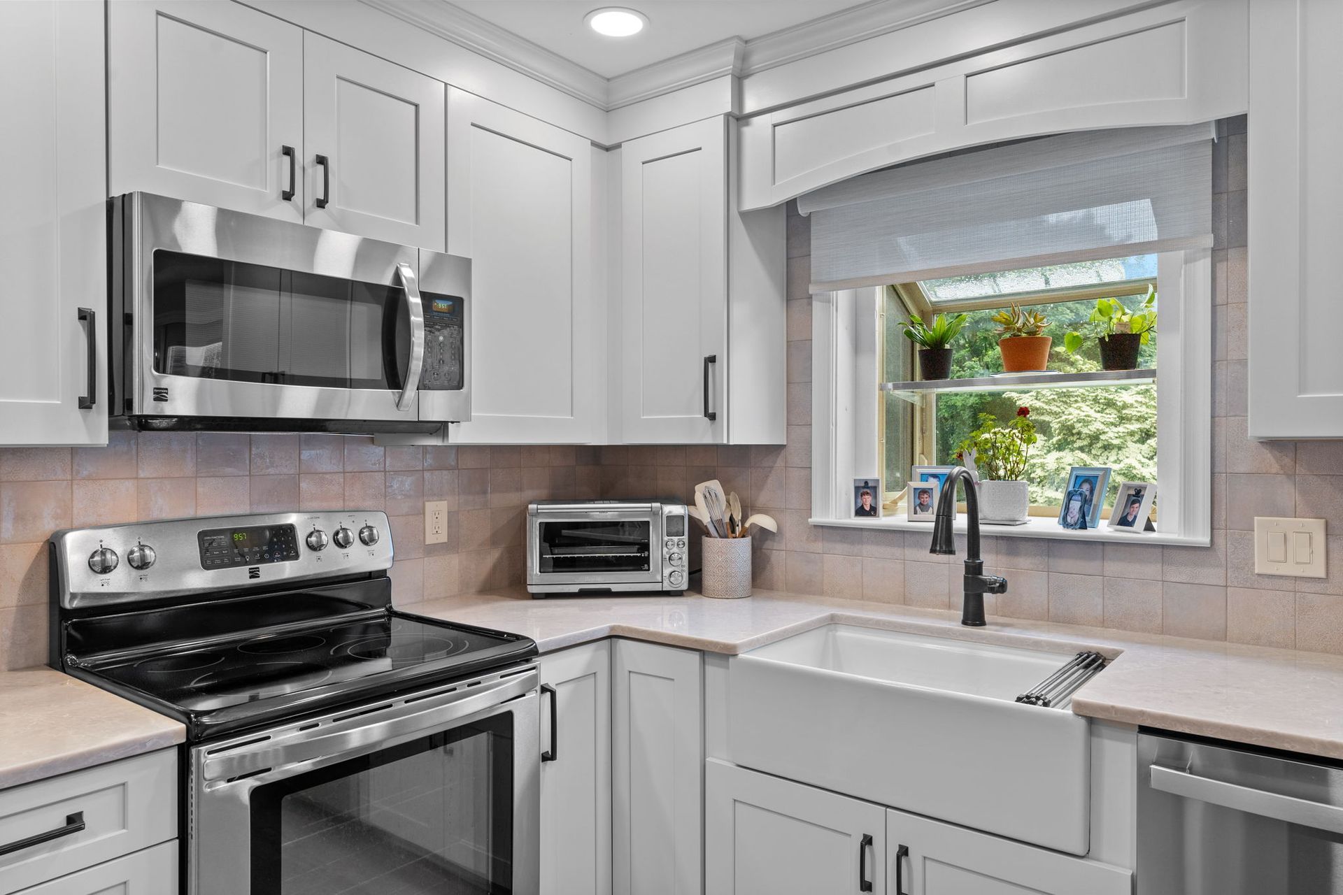 Bright white kitchen with stainless steel appliances, gray cabinets, and a window over the sink  In Bucks County PA