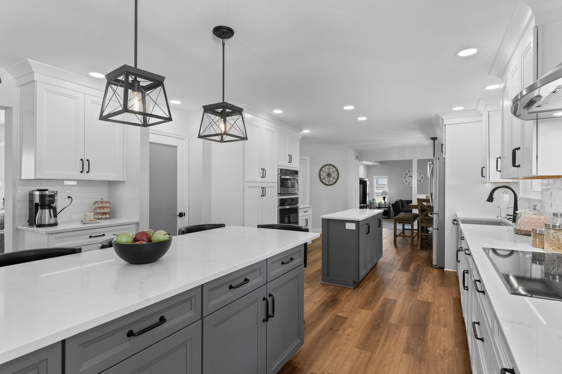 Bright modern kitchen with white cabinets, gray island, pendant lights, and wood floors In Bucks County PA