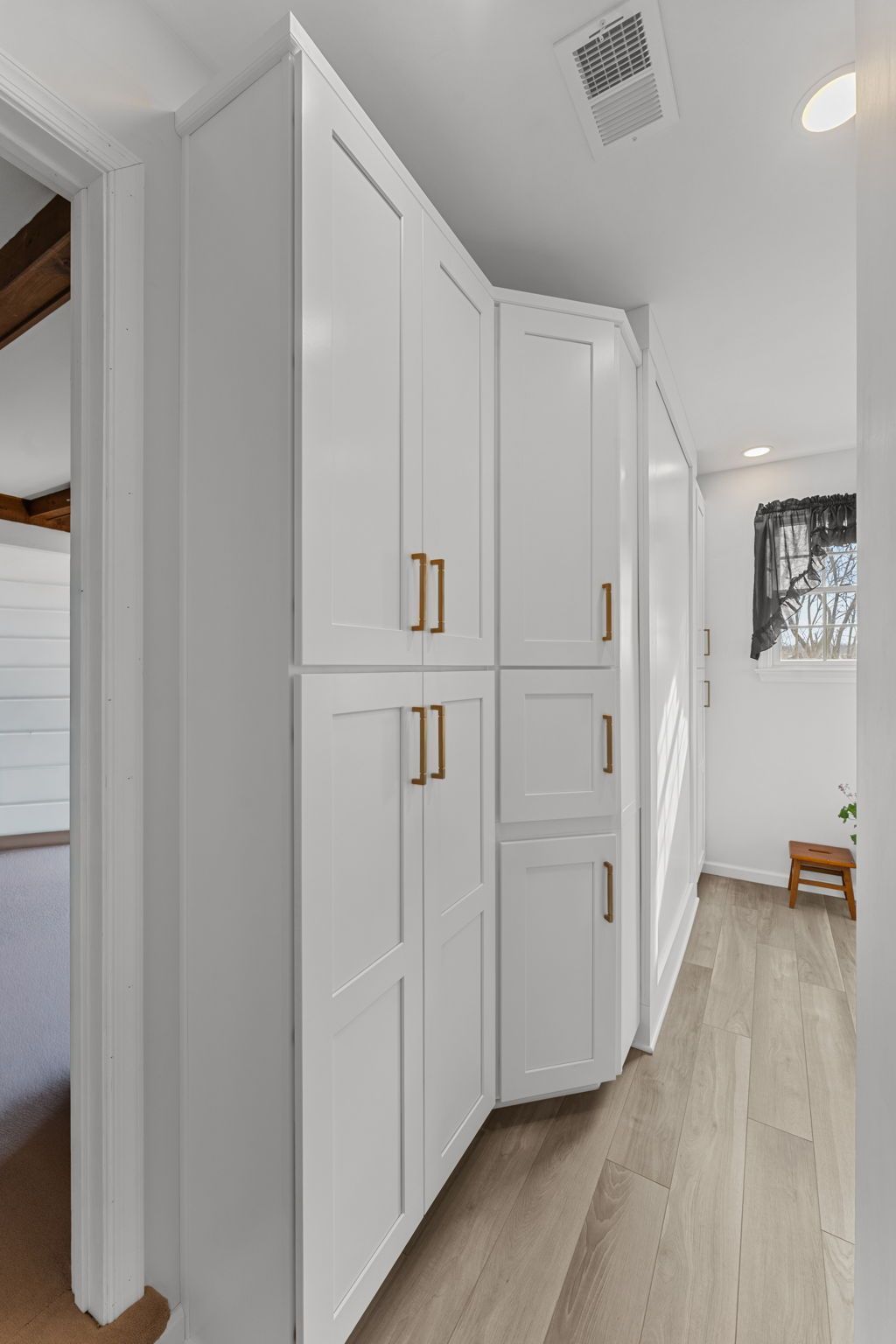 Bright hallway with white built-in cabinets, light wood floors, and a window at the far end In Bucks County PA