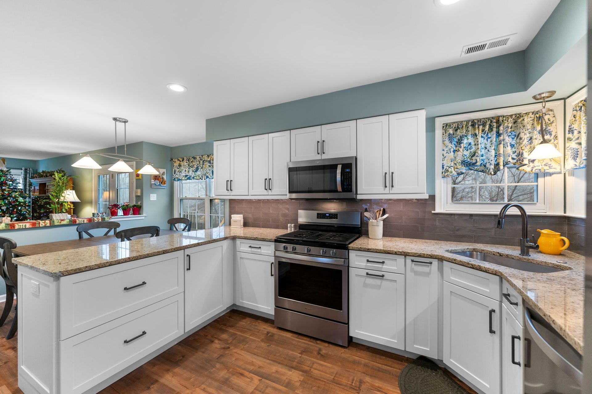 Bright modern kitchen with white cabinets, granite counters, stainless steel stove, and wood floors In Bucks Country PA