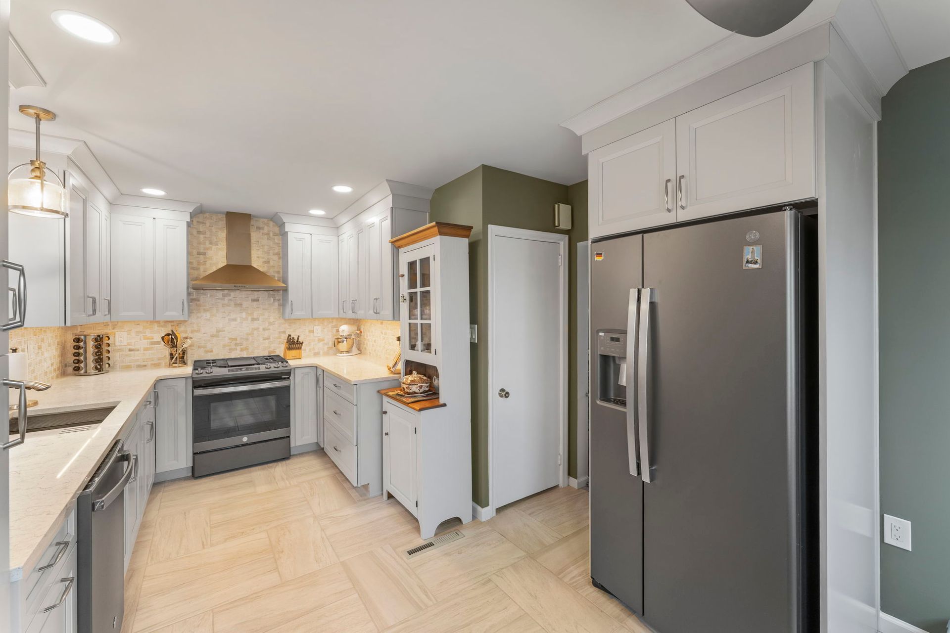 Bright modern kitchen with white cabinets, gray counters, stainless steel fridge, and tiled backsplash In Bucks County PA