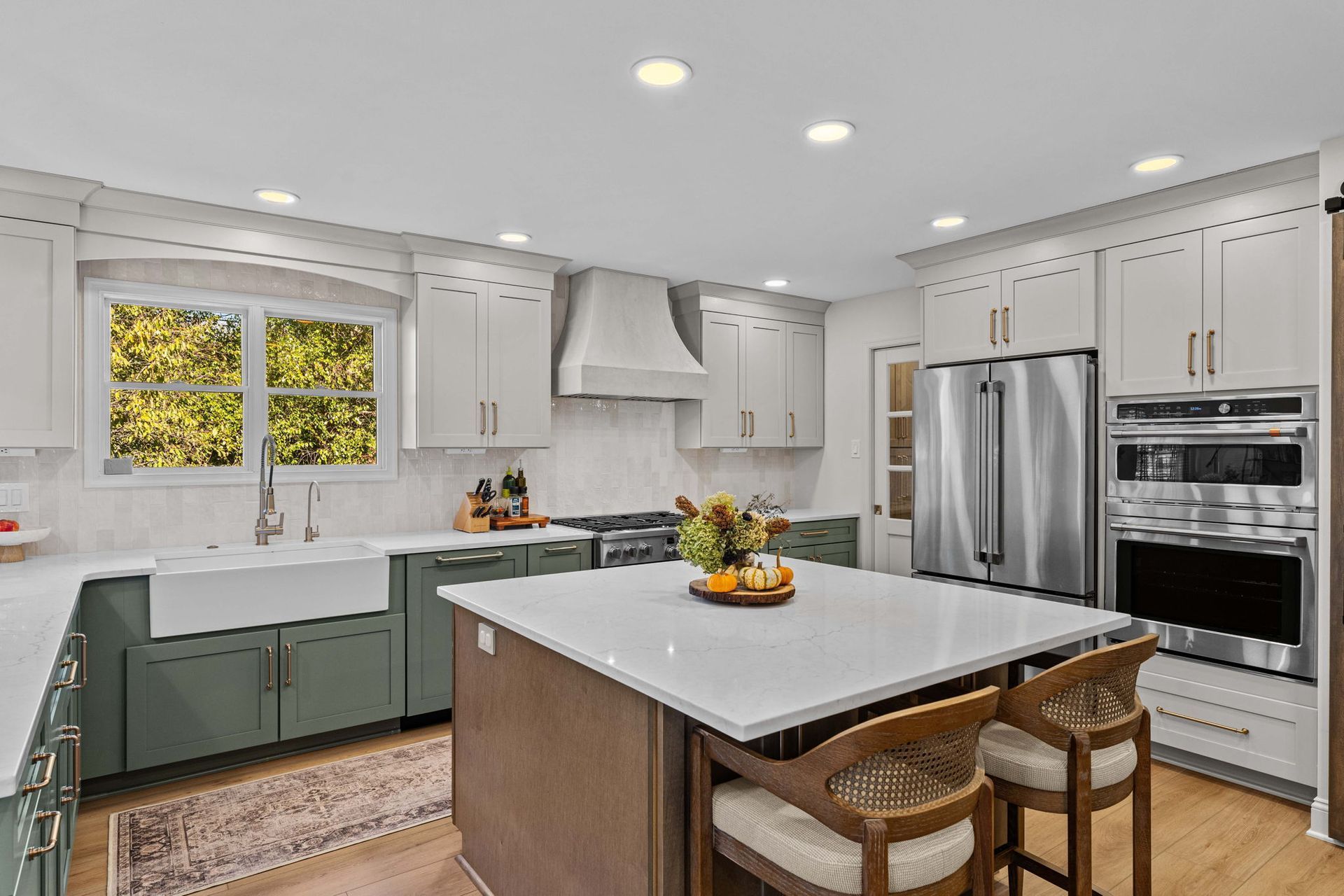 Bright modern kitchen with white cabinets, stainless appliances, island, and green lower cabinets in Bucks County PA