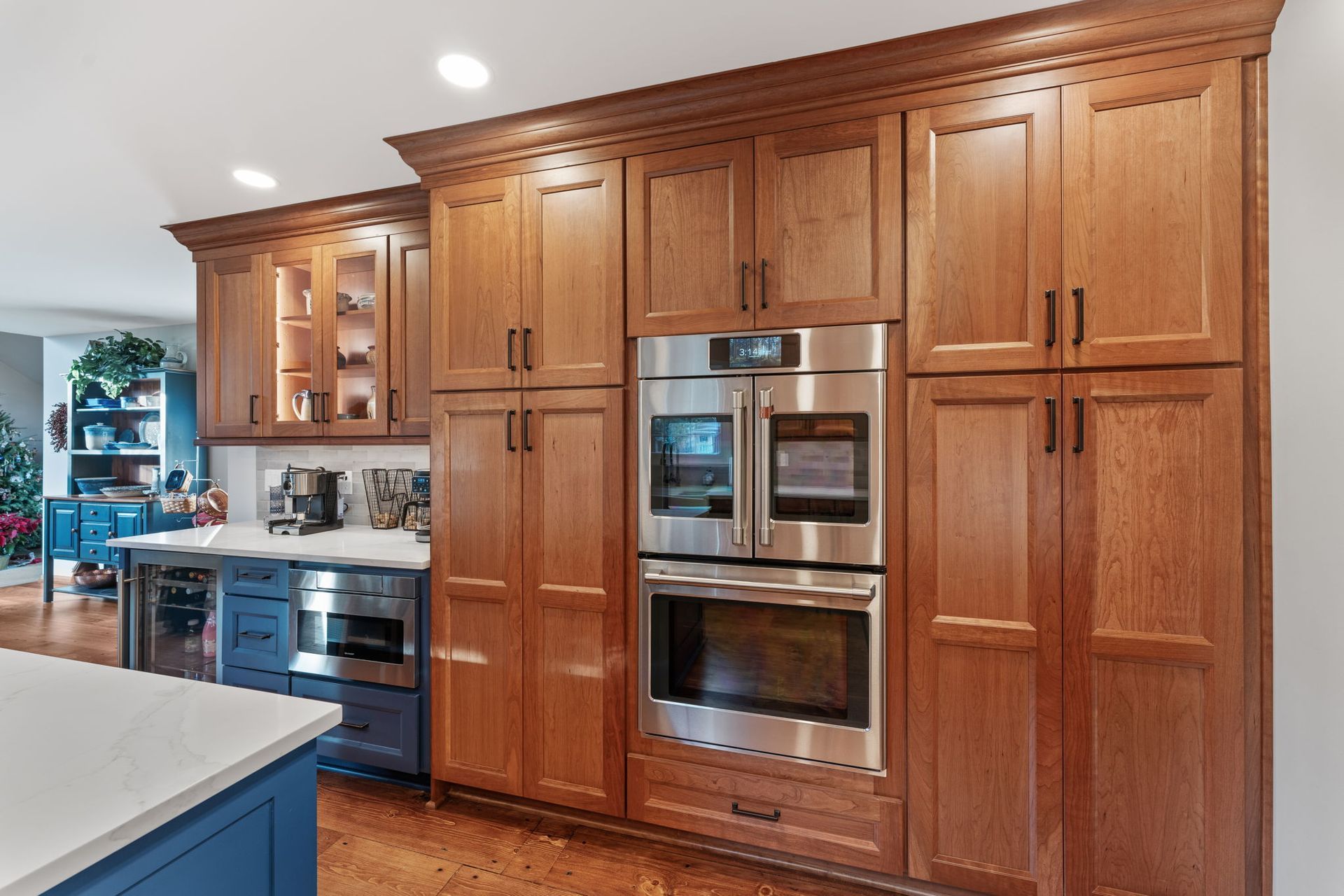 Modern kitchen with wood cabinets, built-in double ovens, and blue island countertop In Bucks County PA