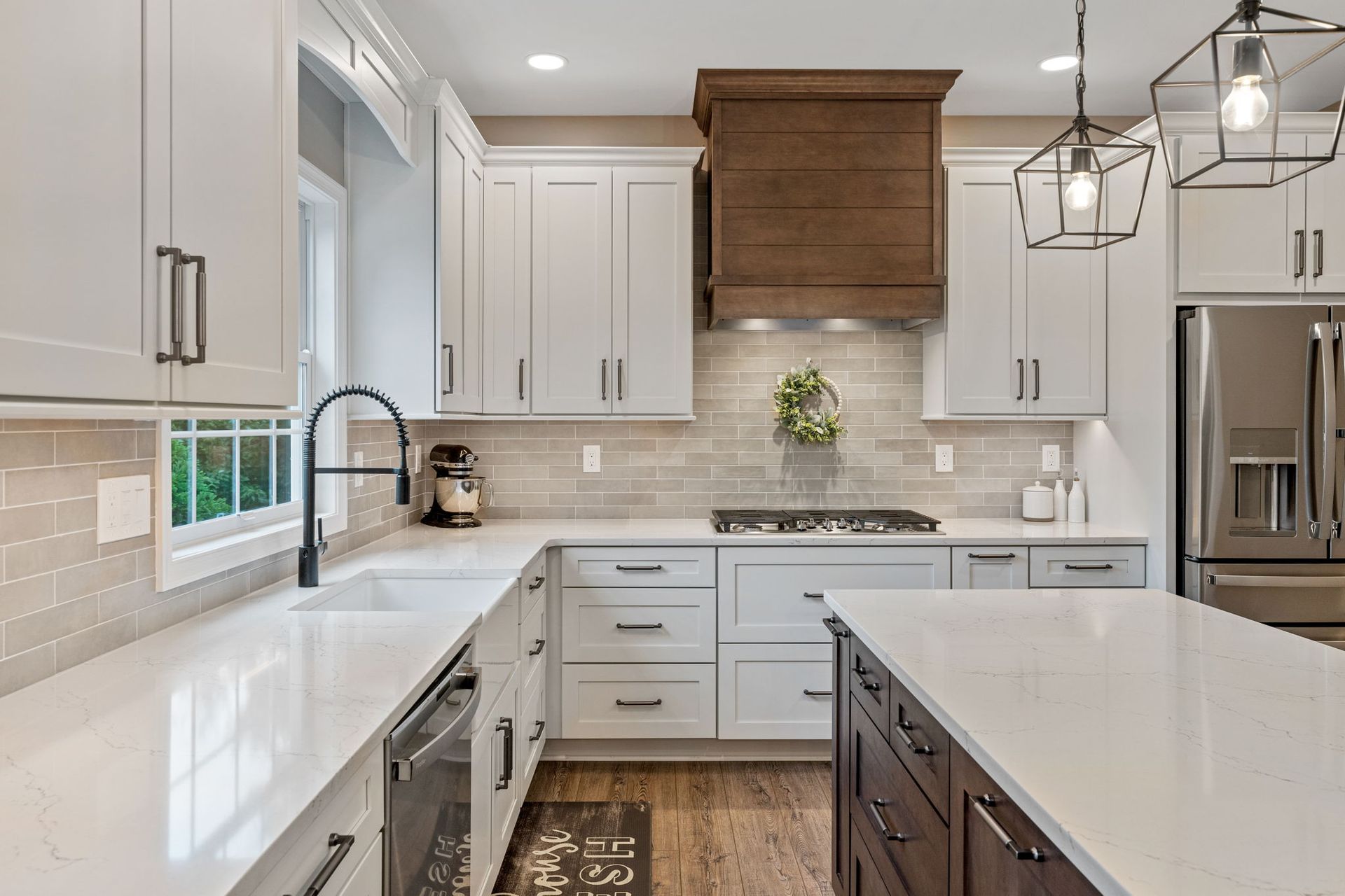 Bright modern kitchen with white cabinets, marble island, and wood range hood Montgomery County PA