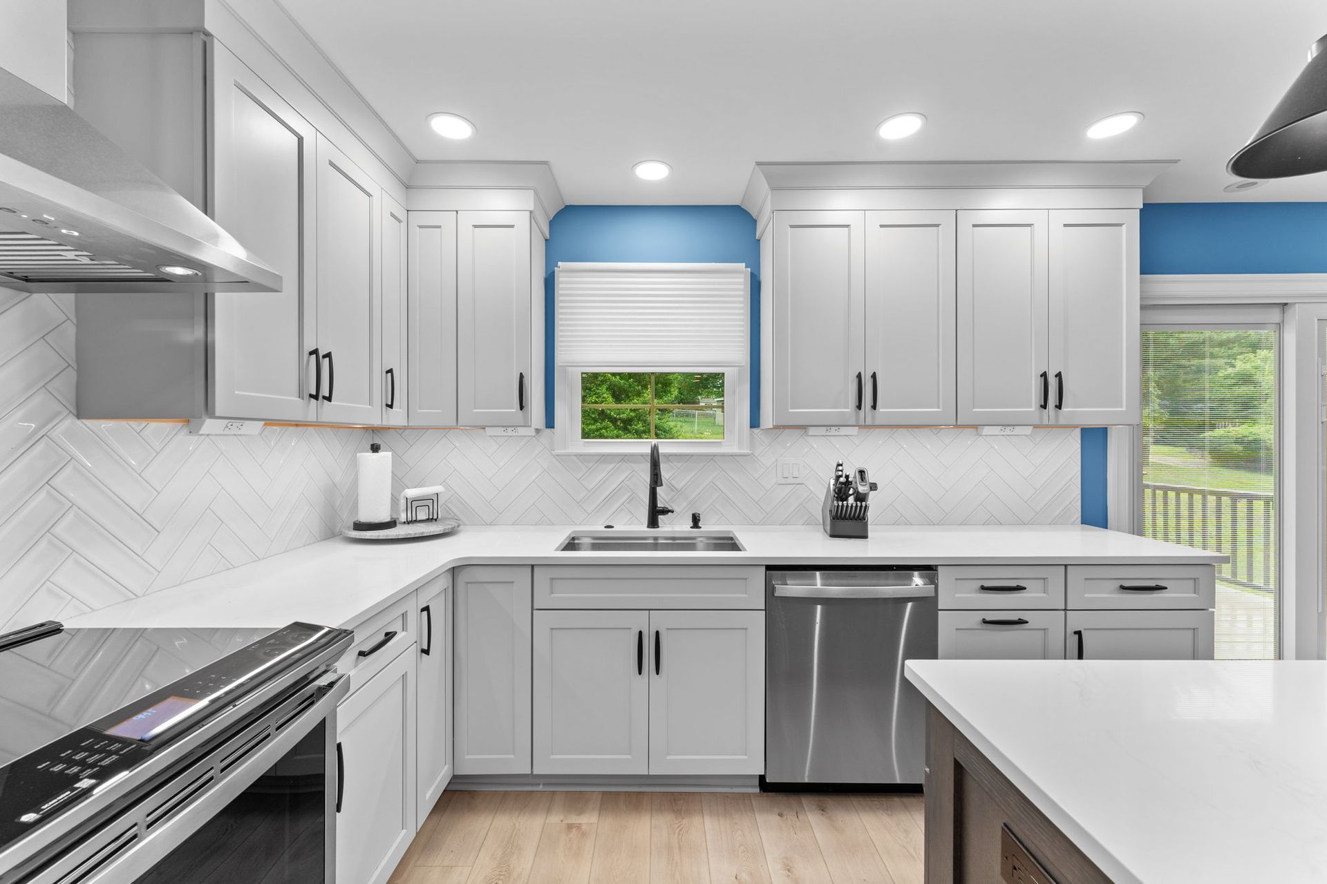 Bright modern kitchen with white cabinets, gray island, stainless appliances, and blue accent wall in Bucks County PA