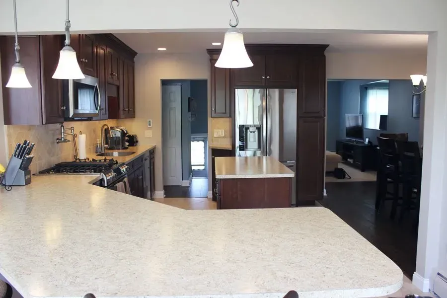 Modern kitchen with large island, pendant lights, dark cabinets, and an open view into adjacent rooms  In Bucks County PA
