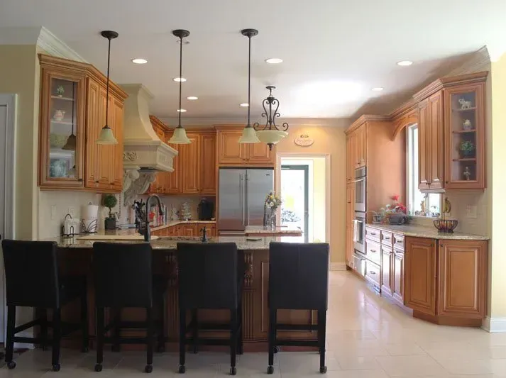 Spacious kitchen with wood cabinets, stainless steel appliances, and a dark island with bar stools  In Bucks County PA