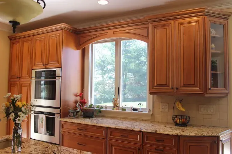 Bright kitchen with wood cabinets, double wall ovens, and a large window over the sink  In Bucks County PA