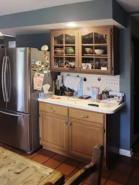 Kitchen nook with stainless refrigerator, wooden hutch, and countertop under warm ceiling light  In Bucks County PA