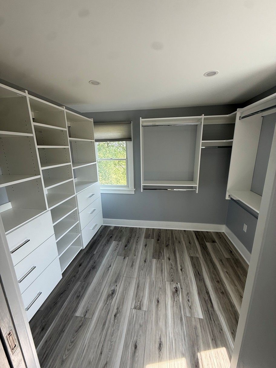 Empty walk-in closet with white shelving, gray walls, and wood-look flooring In Bucks County PA