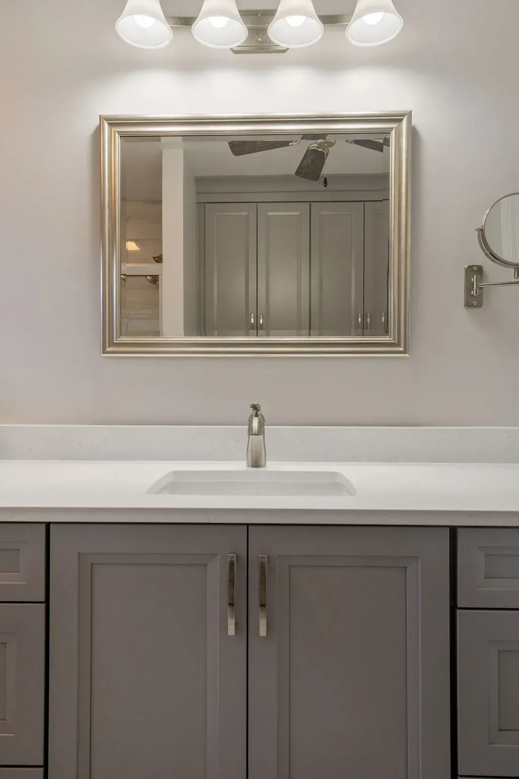 Modern bathroom vanity with gray cabinets, white countertop, mirror, and light fixture above sink In Bucks County PA