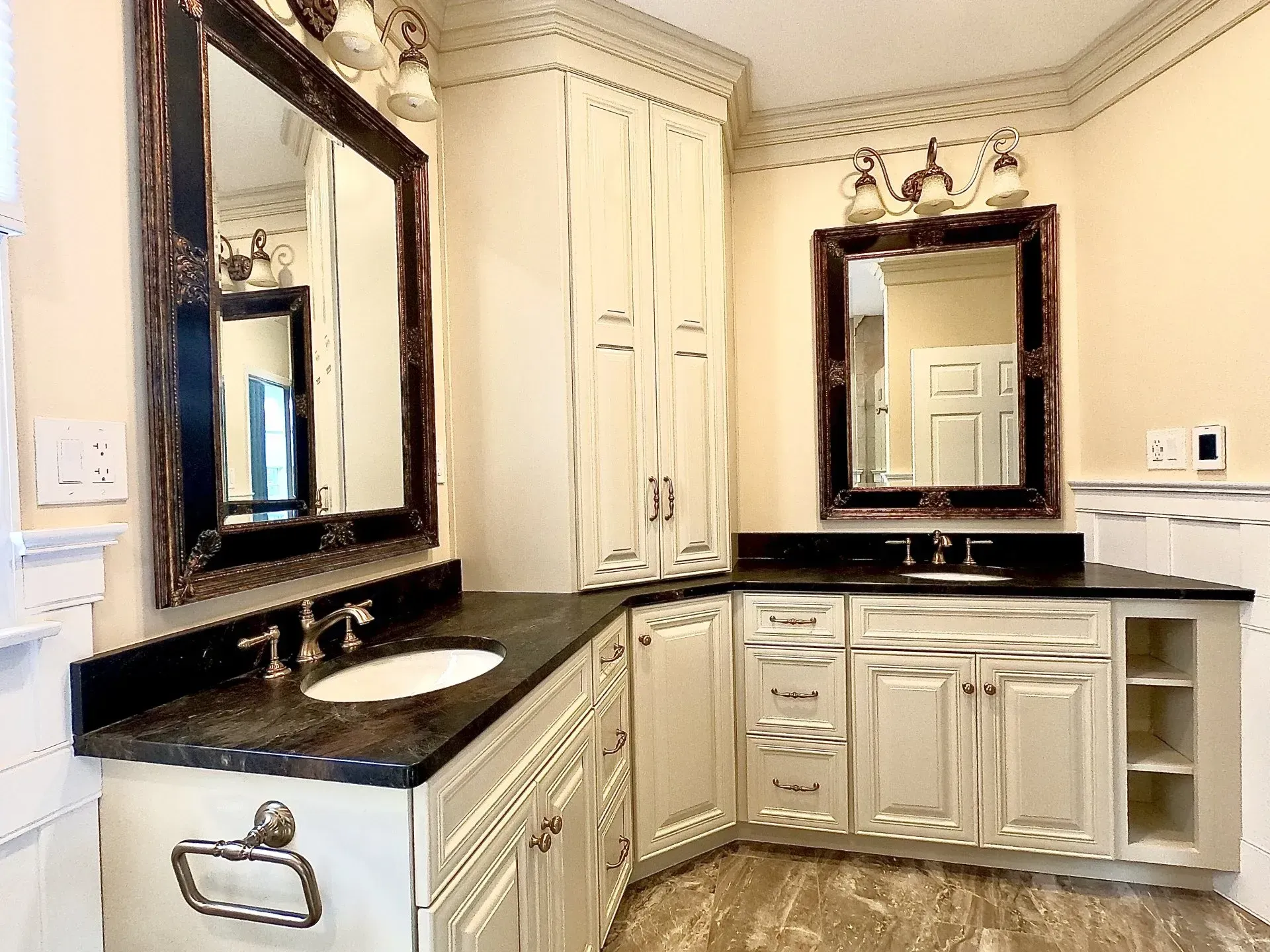 Elegant cream bathroom with dark countertops, large mirrors, and built-in cabinets  In Bucks County PA
