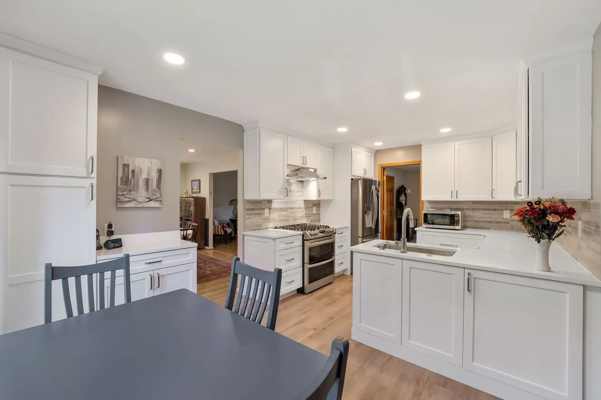 Bright white kitchen with island, dining table, wood floors, and recessed lighting in  Bucks County PA