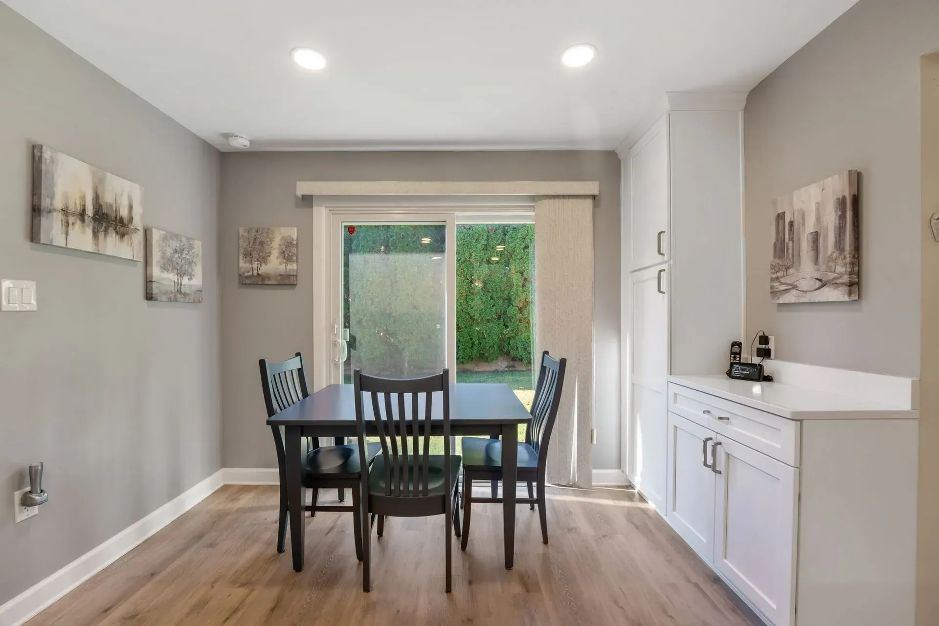Bright dining room with a black table, six chairs, sliding glass door, and white sideboard in Bucks County PA
