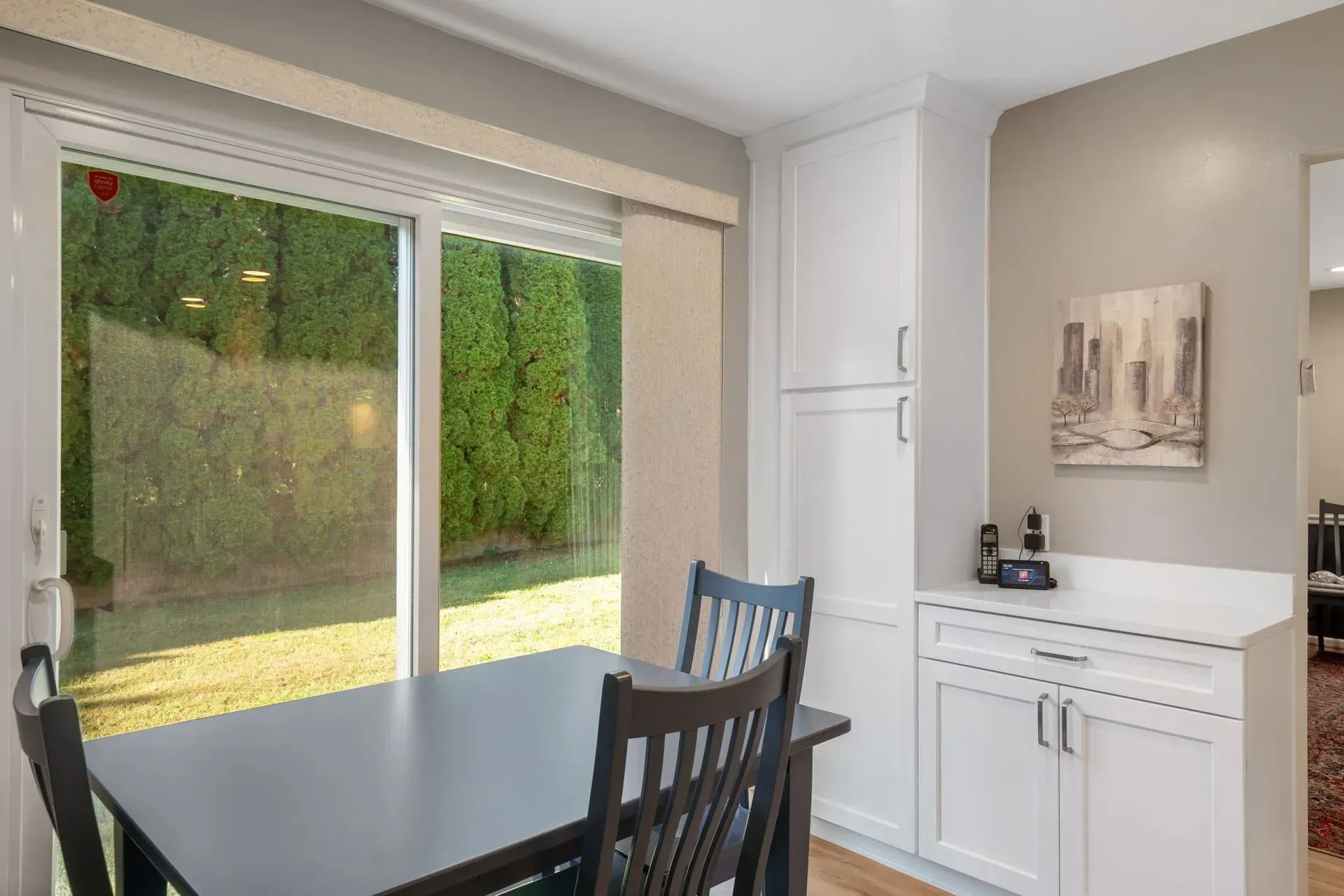 Bright dining area with black table, blue chairs, sliding glass doors, and a white cabinet in Bucks County PA