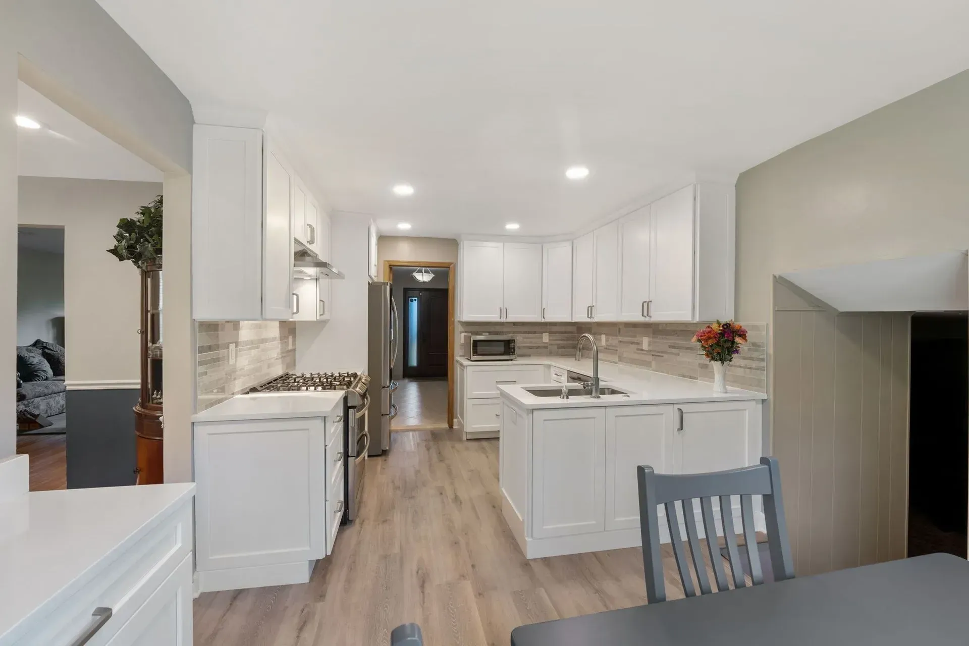 Bright white kitchen and dining area with island, recessed lights, and open doorway to hallway in Bucks County PA