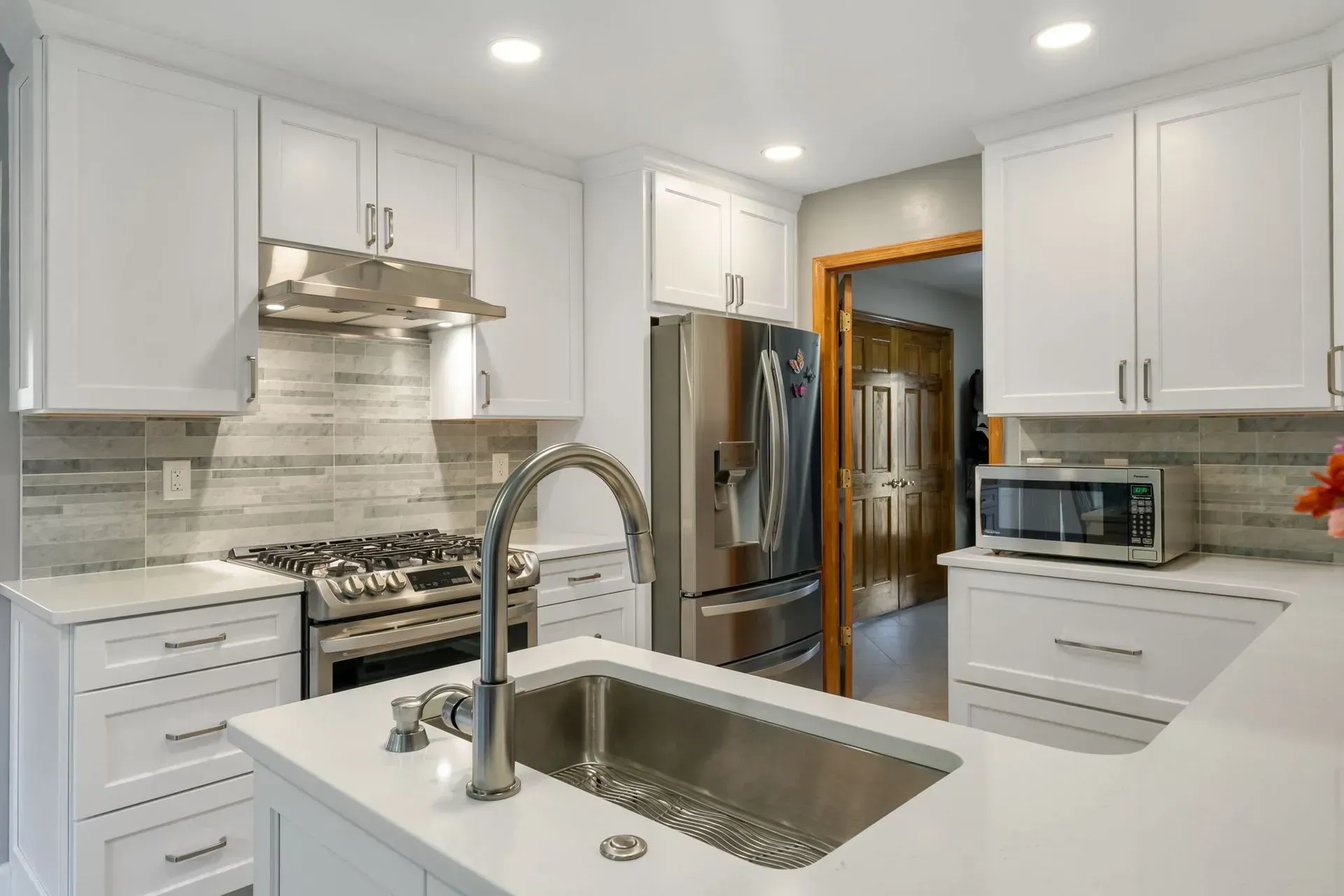 Bright white modern kitchen with stainless steel appliances and a large island sink in Bucks County PA