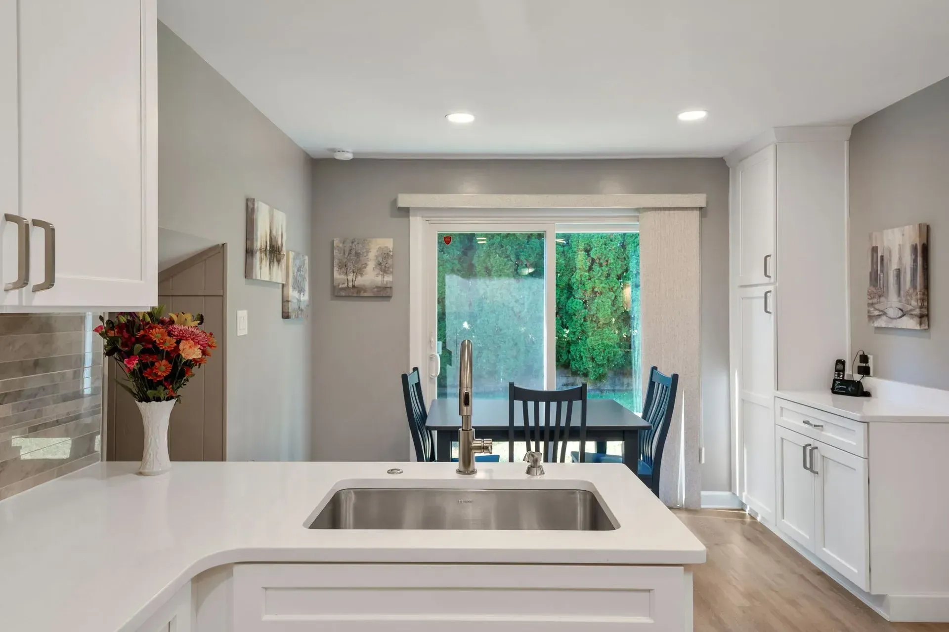 Bright kitchen with white island, sink, dining table, and sliding glass doors to a green patio in Bucks County PA