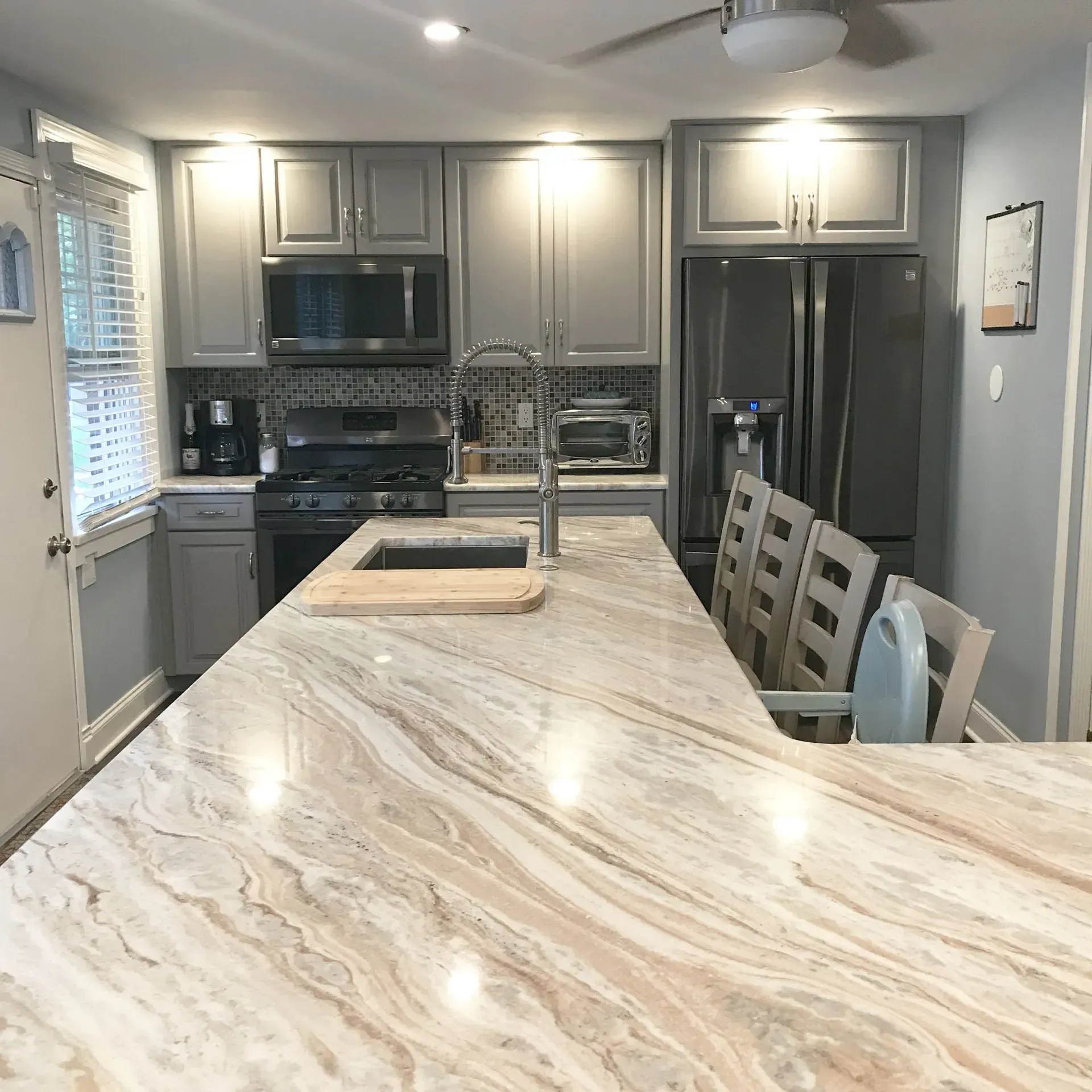 Modern kitchen with marble island, stainless appliances, gray cabinets, and pendant lighting  In Bucks County PA