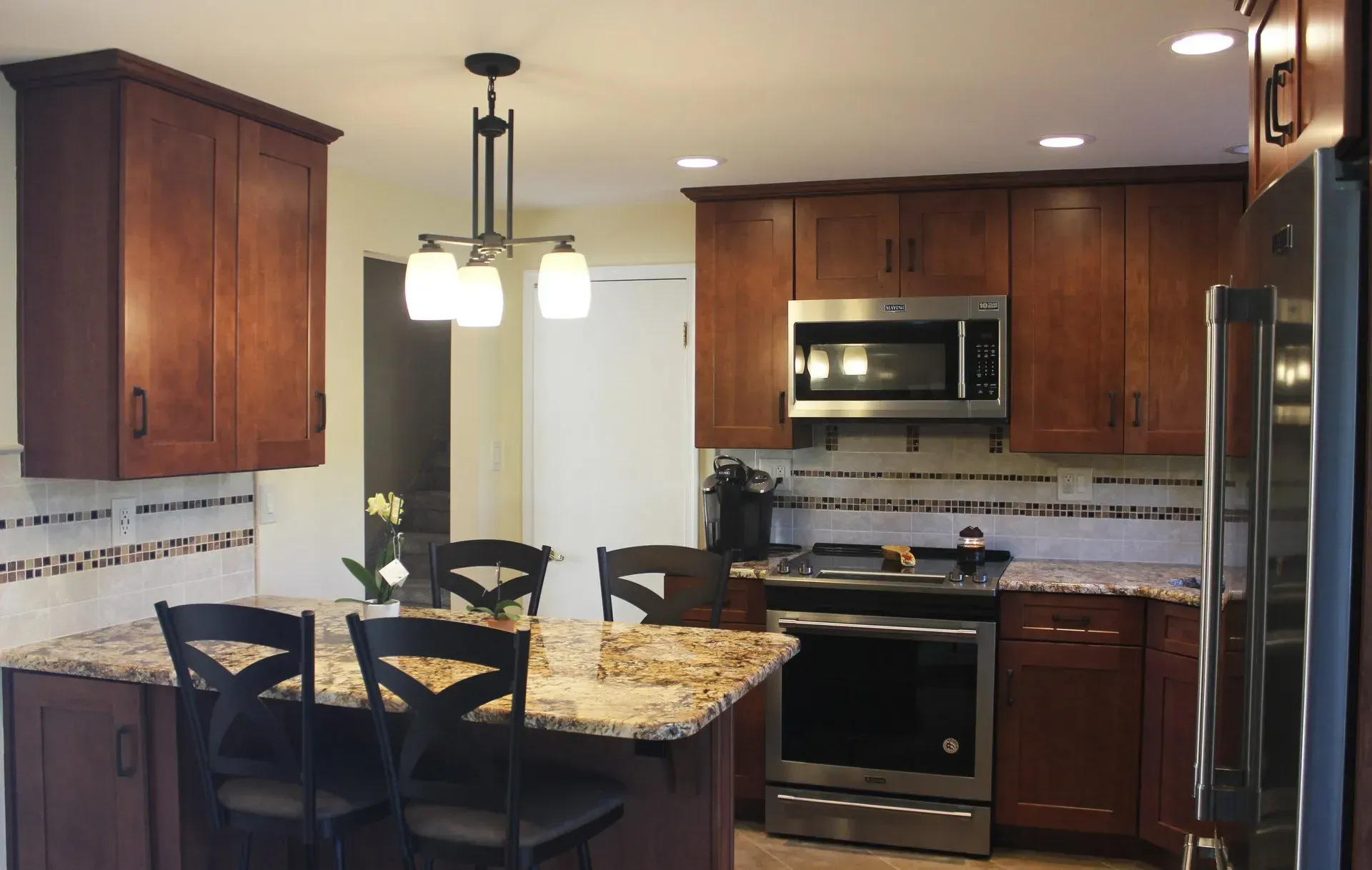 Modern kitchen with granite island, dark wood cabinets, stainless steel appliances, and pendant lights In Bucks County PA