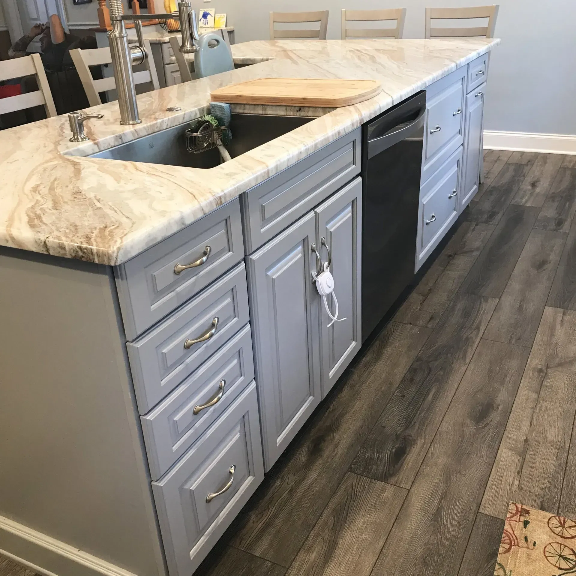 Kitchen island with sink, marble countertop, gray cabinets, and dark wood floor  In Bucks County PA
