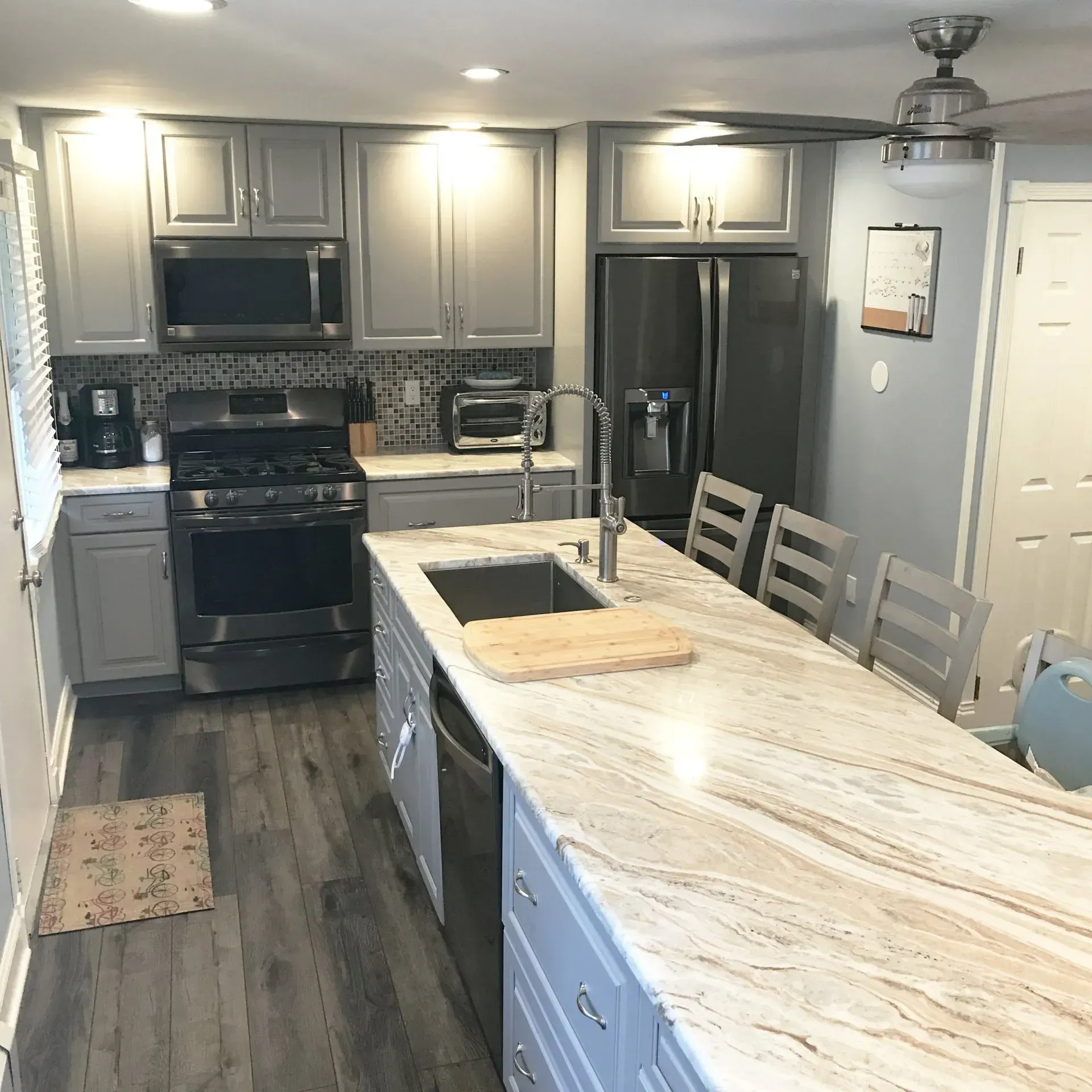 Modern gray kitchen with island, stainless appliances, dark floor, and light countertops  In Bucks County PA