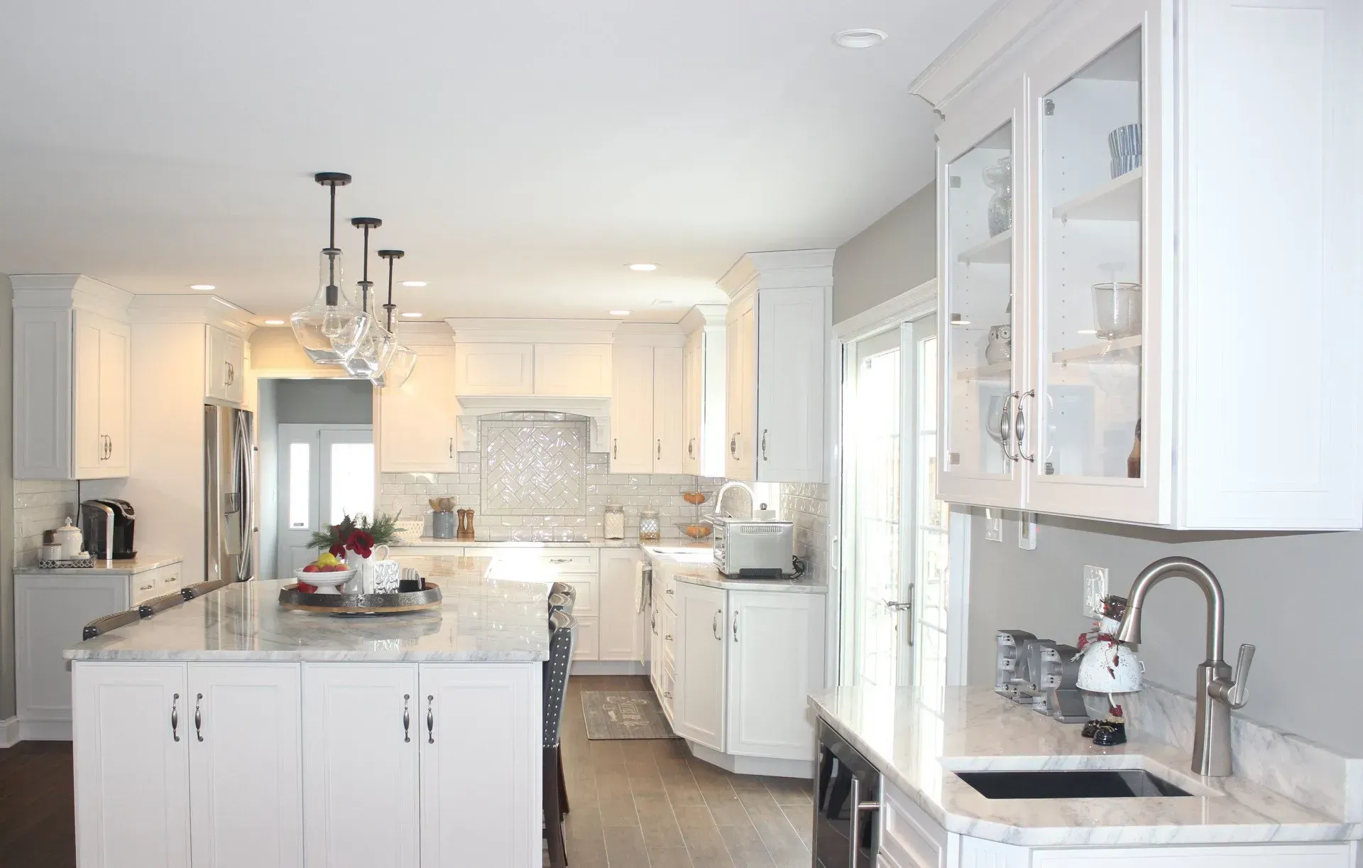 Bright white kitchen with marble island, pendant lights, and glass cabinets In Bucks Country PA