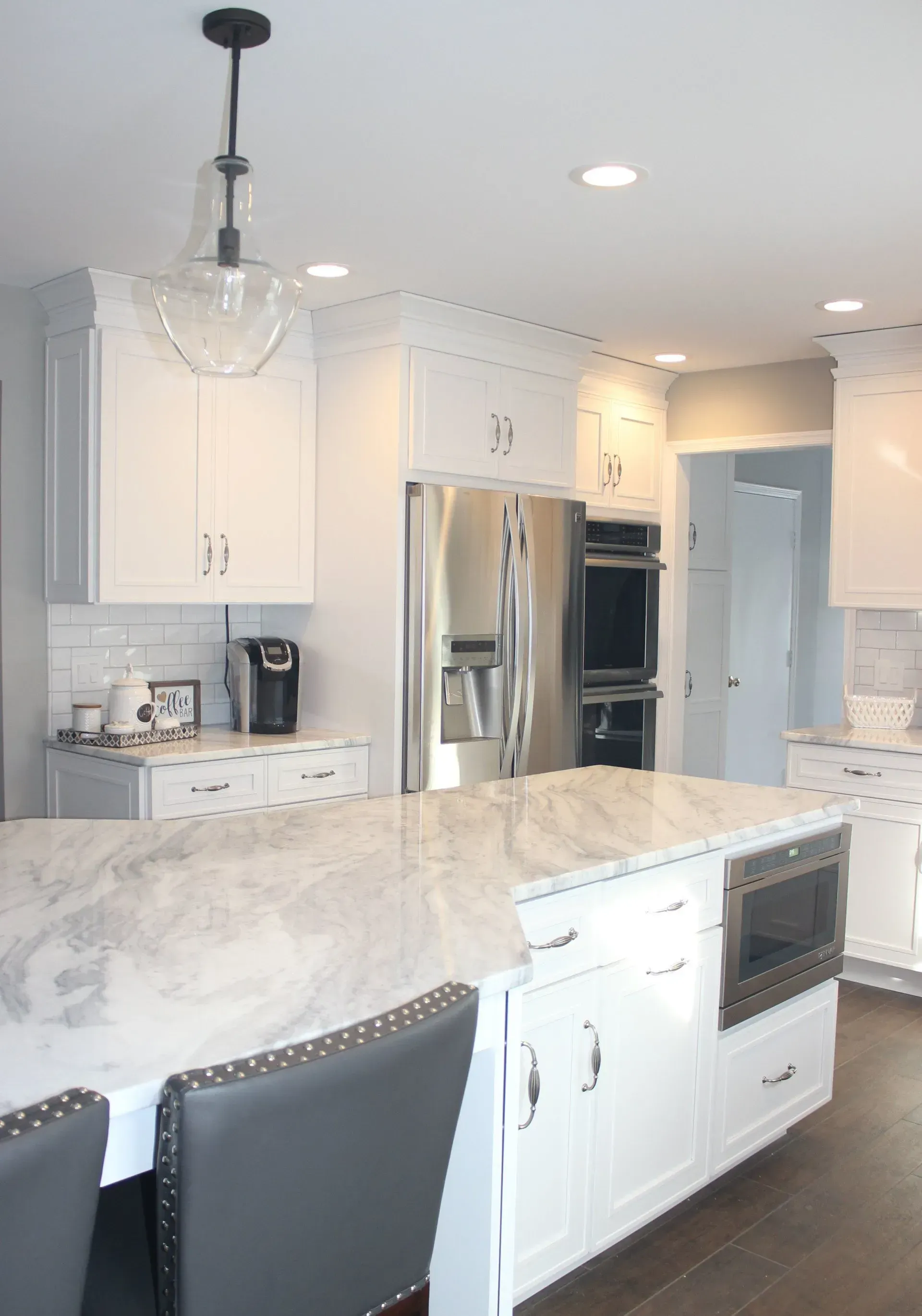 Bright white kitchen with marble island, stainless steel appliances, and pendant lights  In Bucks County PA