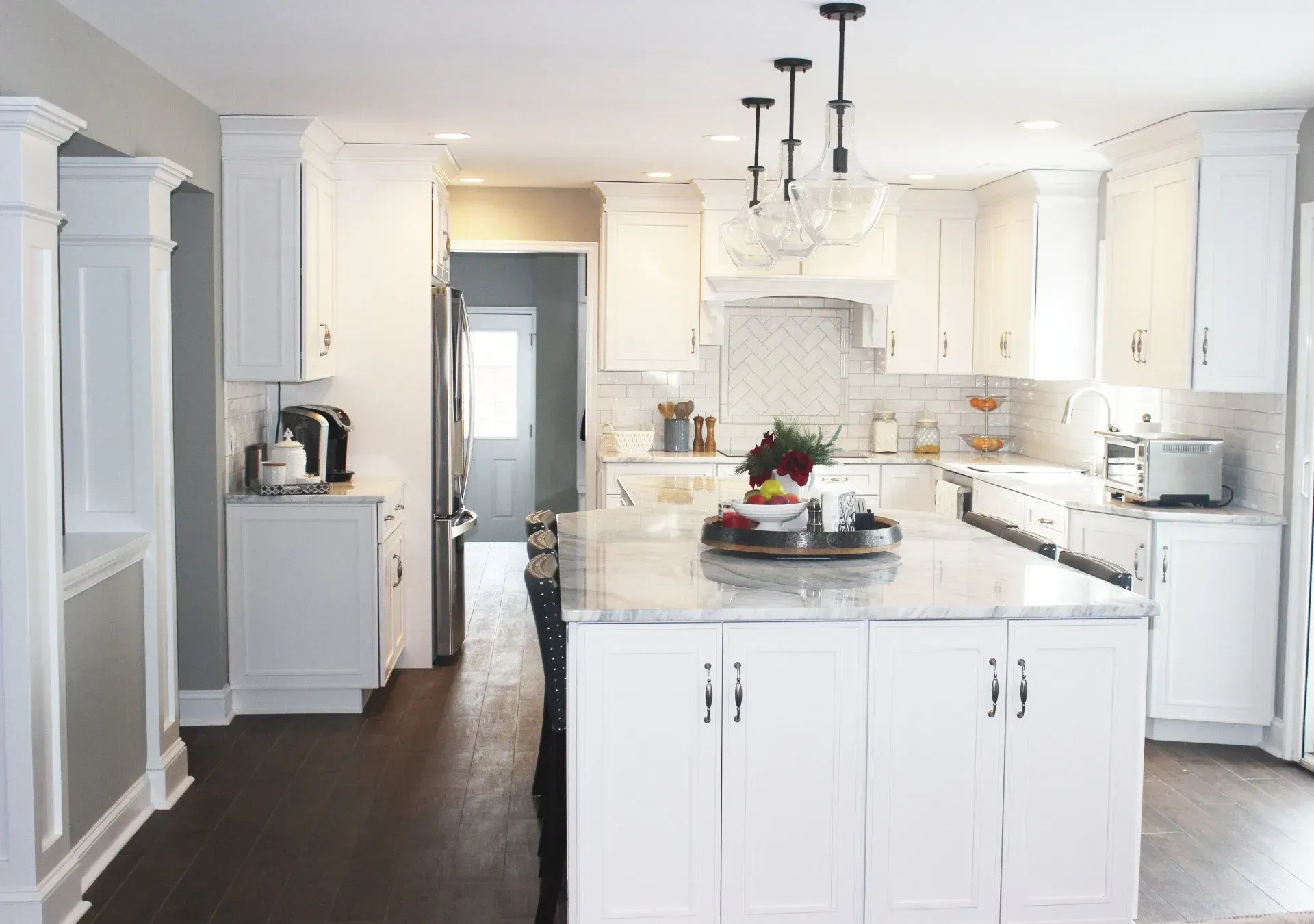 Bright white kitchen with an island, cabinets, pendant lights, and dark wood floors  In Bucks County PA
