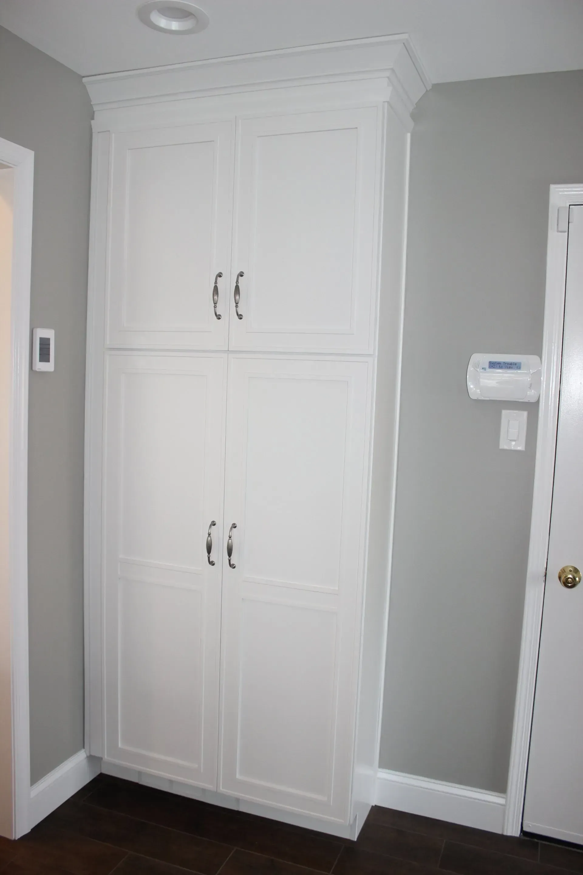 Built-in white storage cabinets in a gray hallway beside a white door  In Bucks County PA