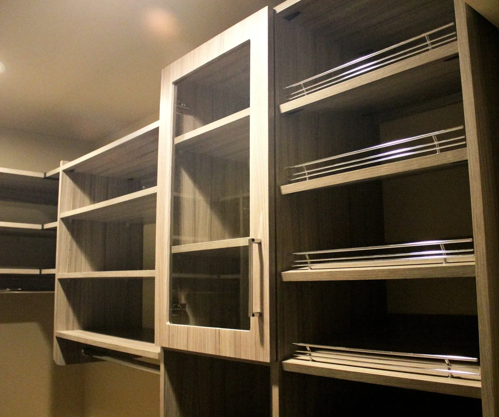 Empty wooden shelving units in a dimly lit room, with one central cabinet featuring a glass door In Bucks Country PA