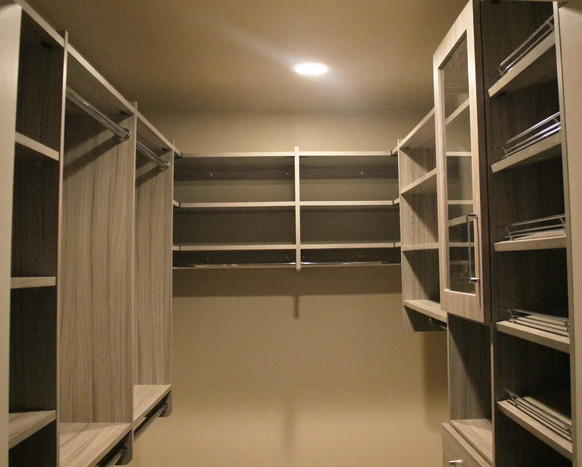Walk-in closet with empty wooden shelves and hanging rods under recessed ceiling light In Bucks Country PA