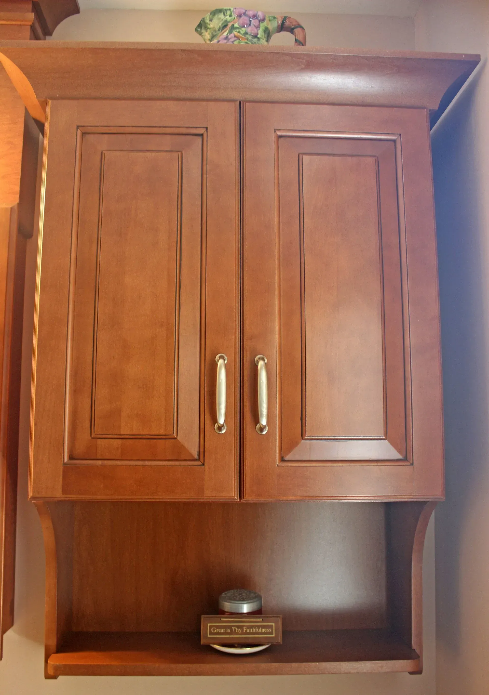 Wooden wall cabinet with two doors above a small open shelf holding a glass jar In Bucks County PA