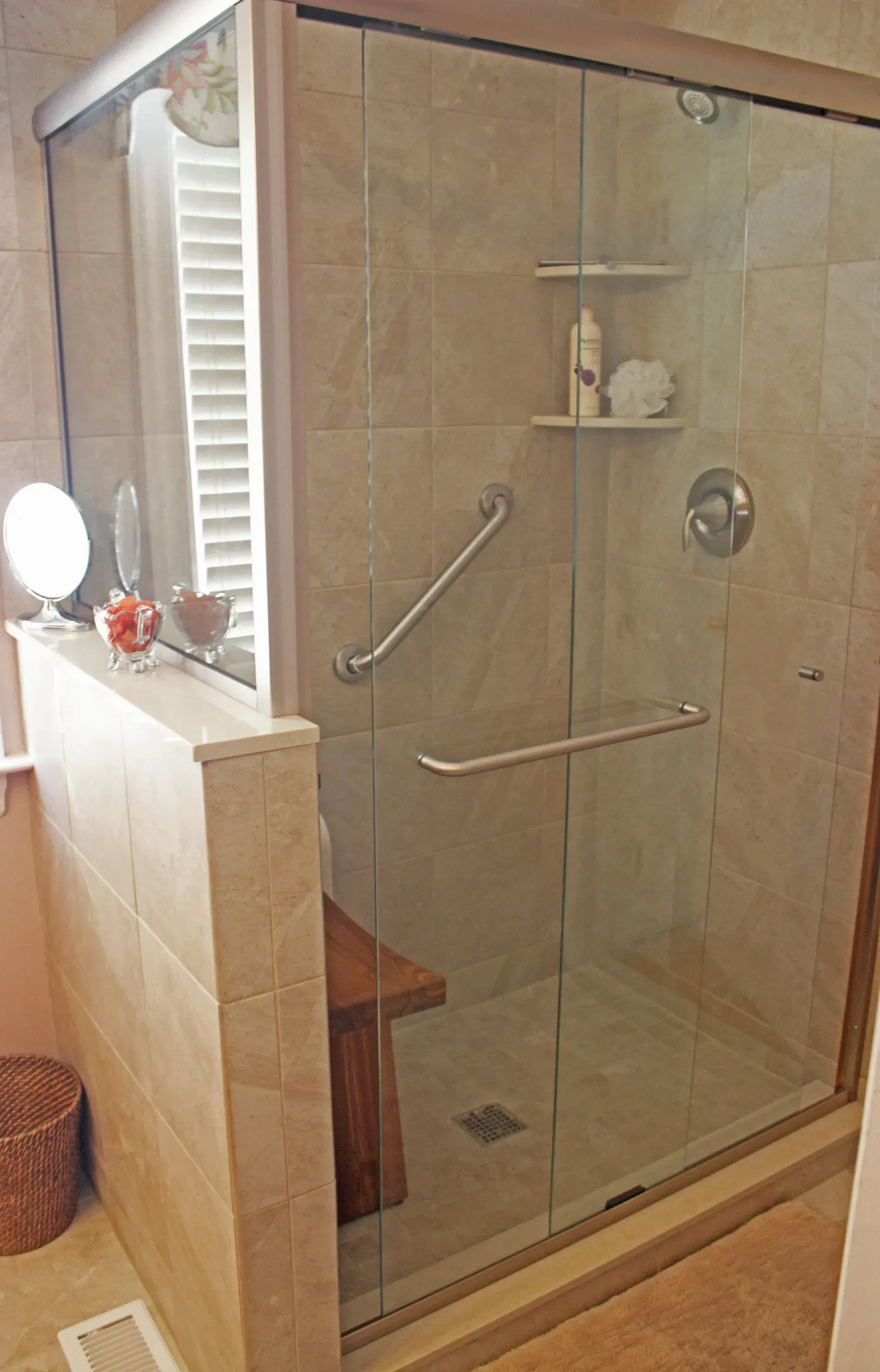 Glass walk-in shower with beige tile, grab bars, and built-in shelf in a bathroom In Bucks County PA