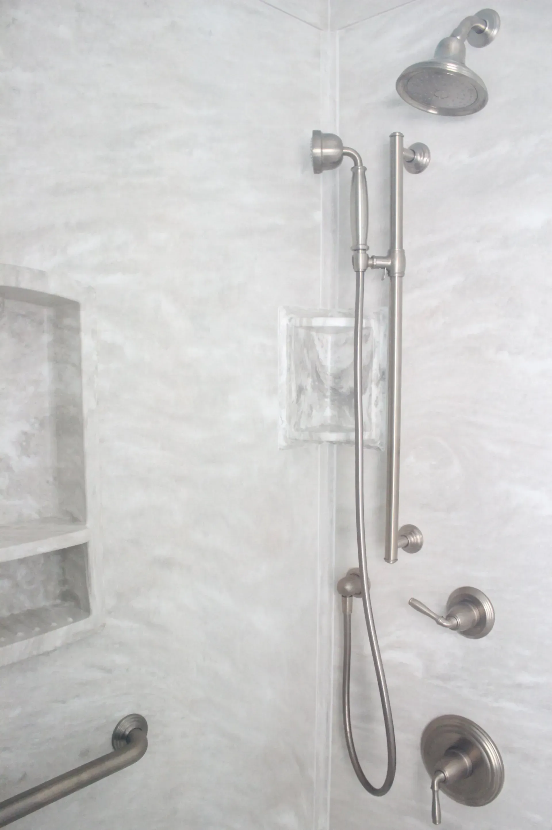 Bathroom shower with chrome grab bars, handheld showerhead, and tiled wall In Bucks County PA