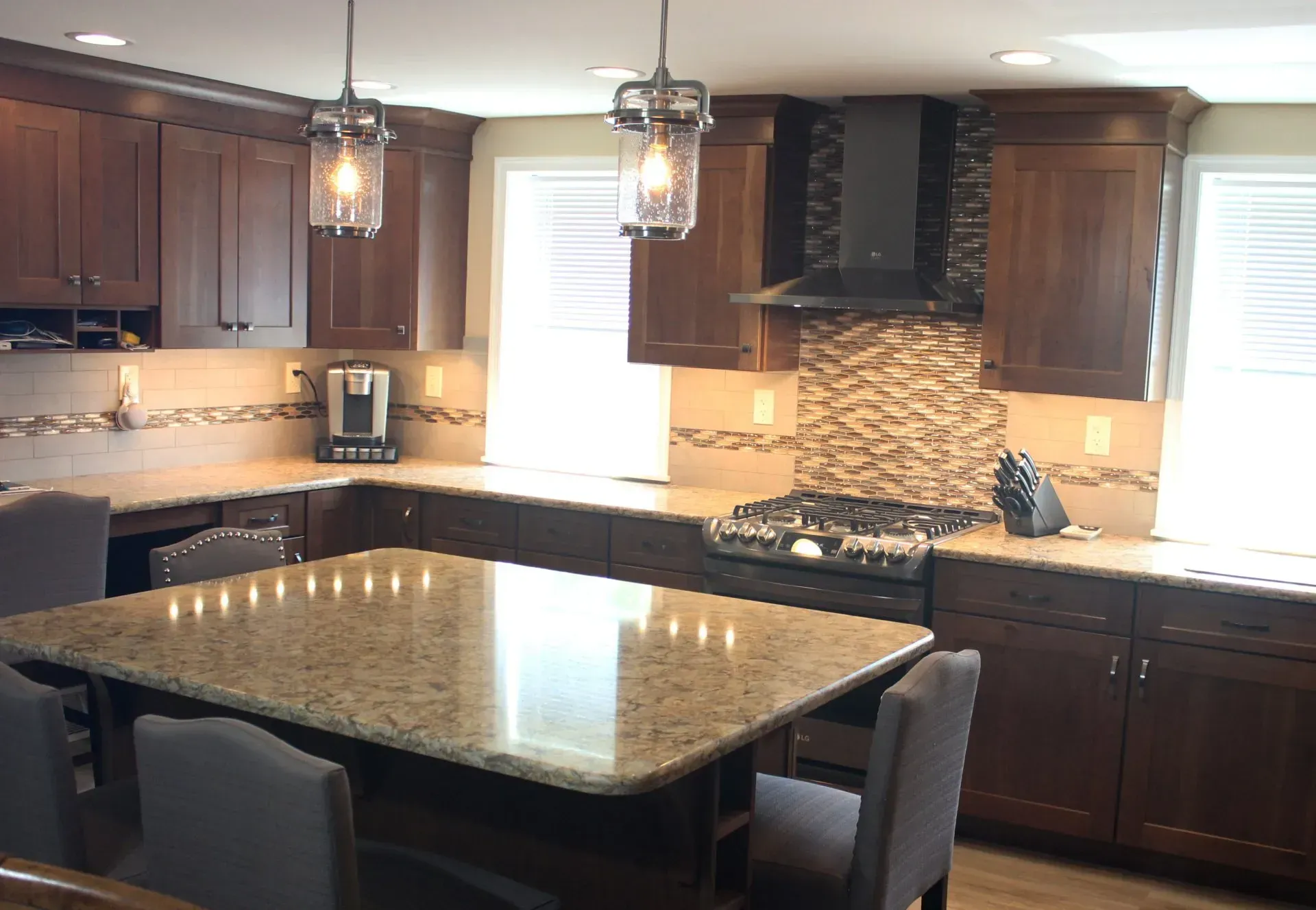 Modern kitchen with dark wood cabinets, granite island, and hanging pendant lights In Bucks Country PA