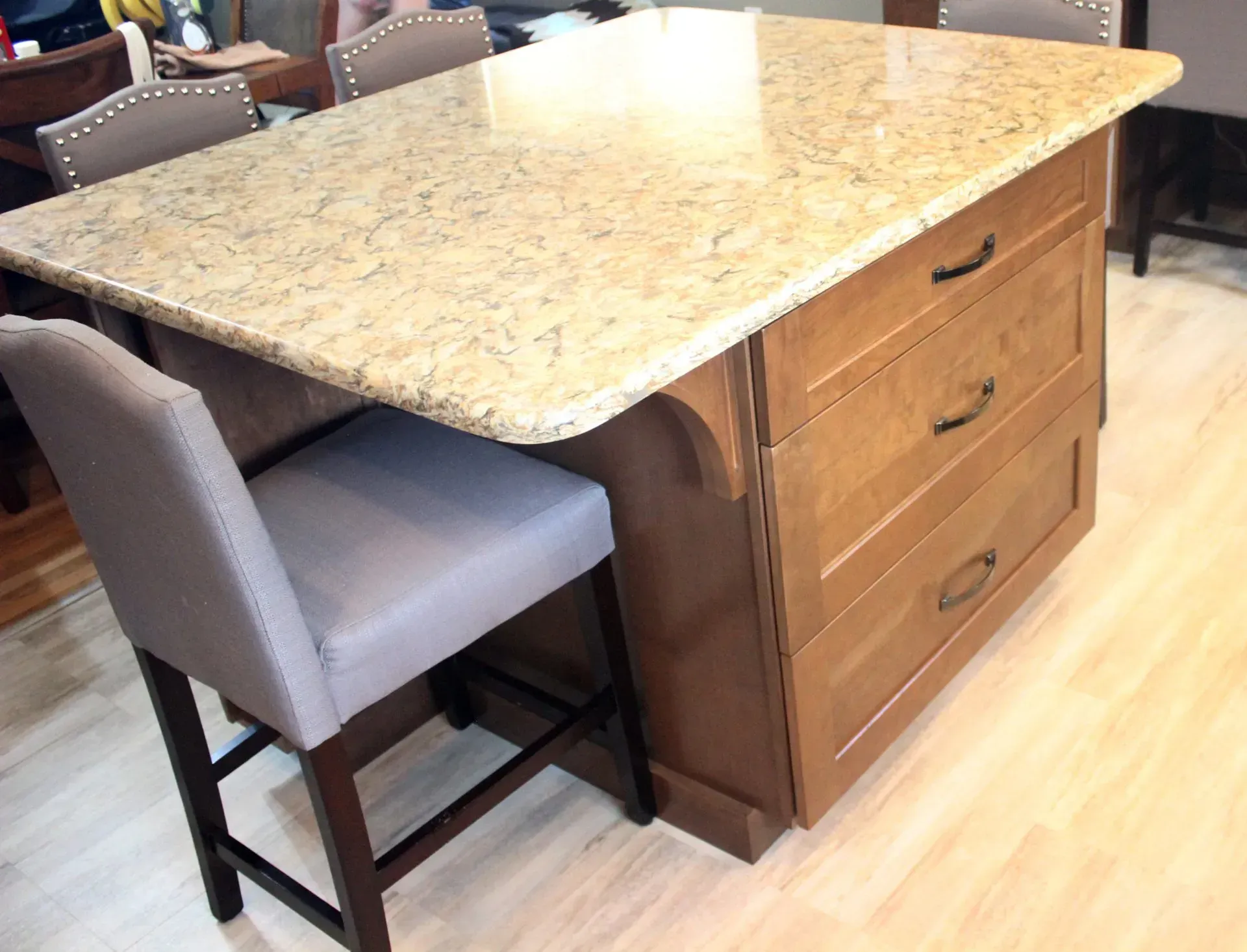 Kitchen island with granite countertop and two gray upholstered stools in a bright room  In Bucks County PA