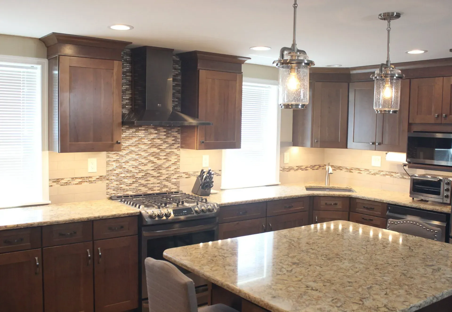 Modern kitchen with dark wood cabinets, granite island, pendant lights, and mosaic backsplash  In Bucks County PA