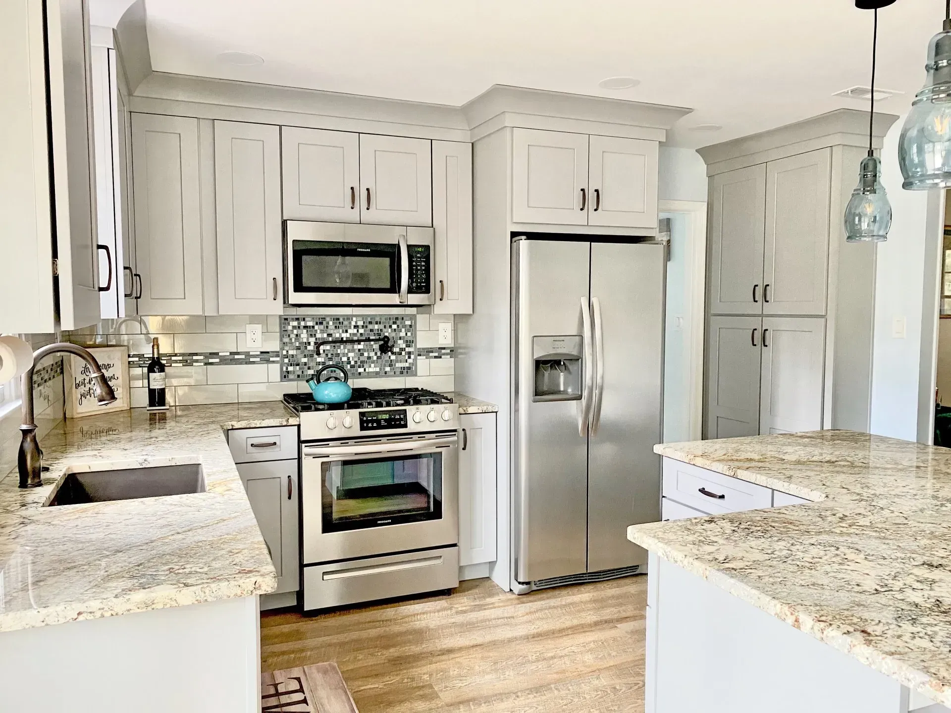 Bright white kitchen with granite countertops, stainless steel appliances, and pendant lights In Bucks Country PA