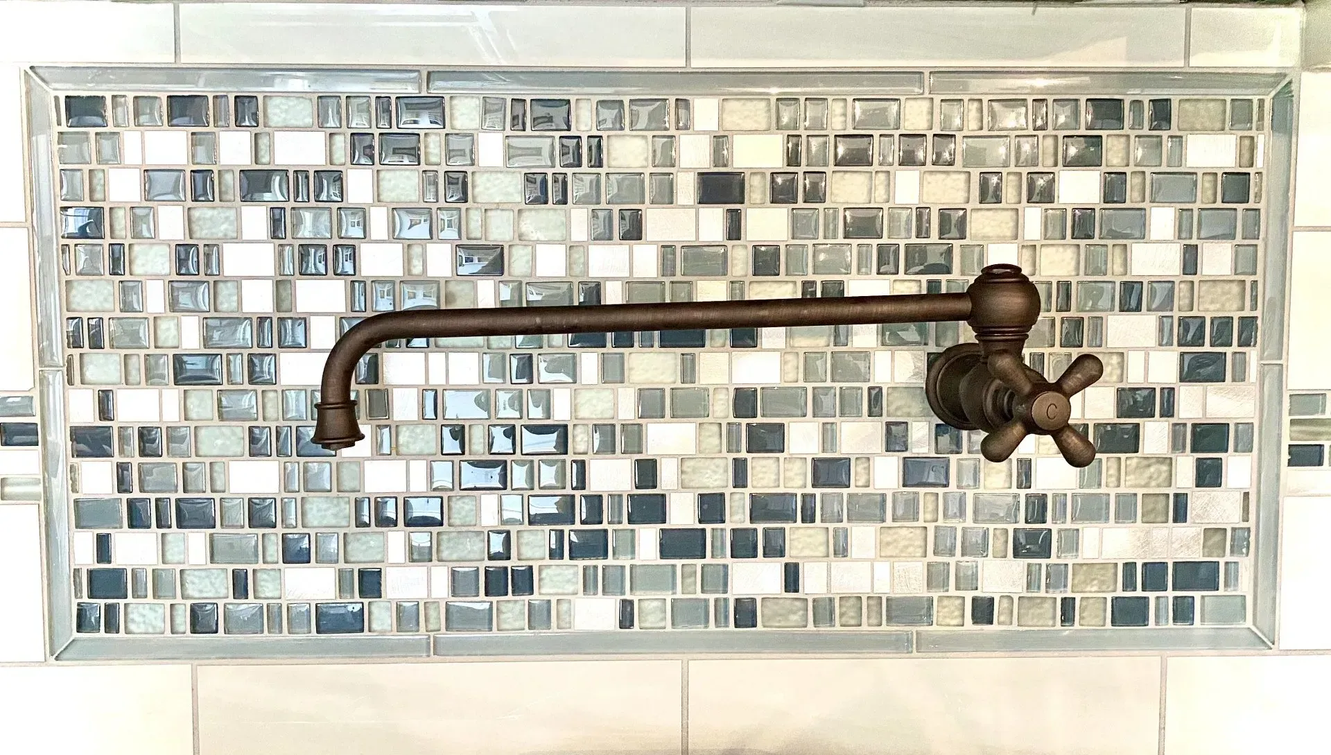 Bronze faucet mounted on a blue-gray mosaic tile wall above a sink or tub  In Bucks County PA