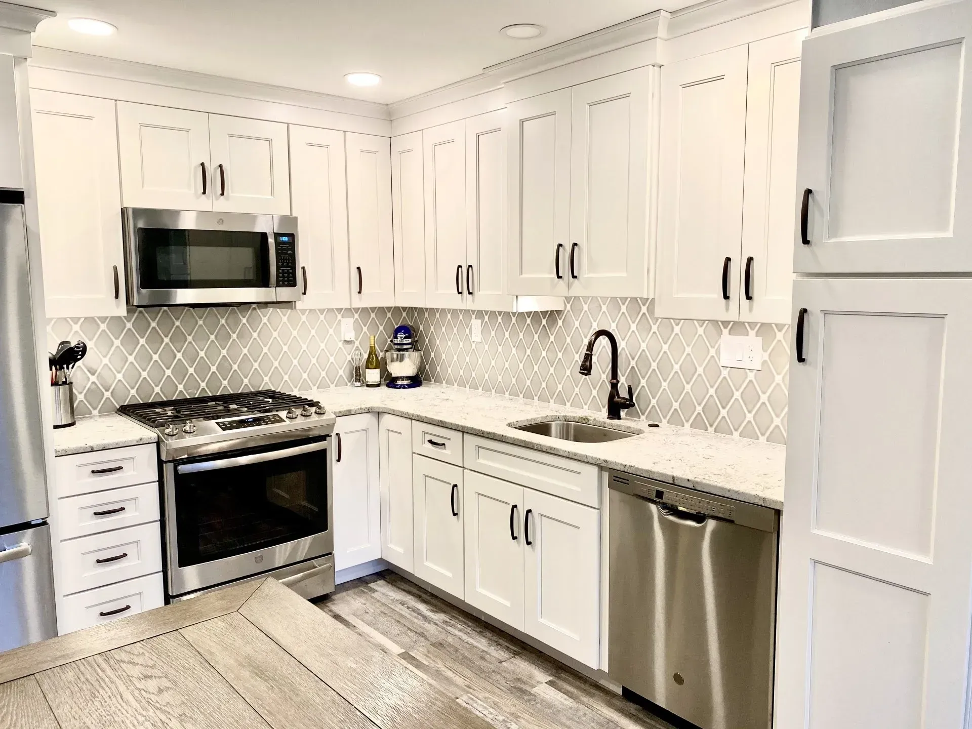Bright white modern kitchen with stainless steel appliances, cabinets, and light wood flooring In Bucks County PA