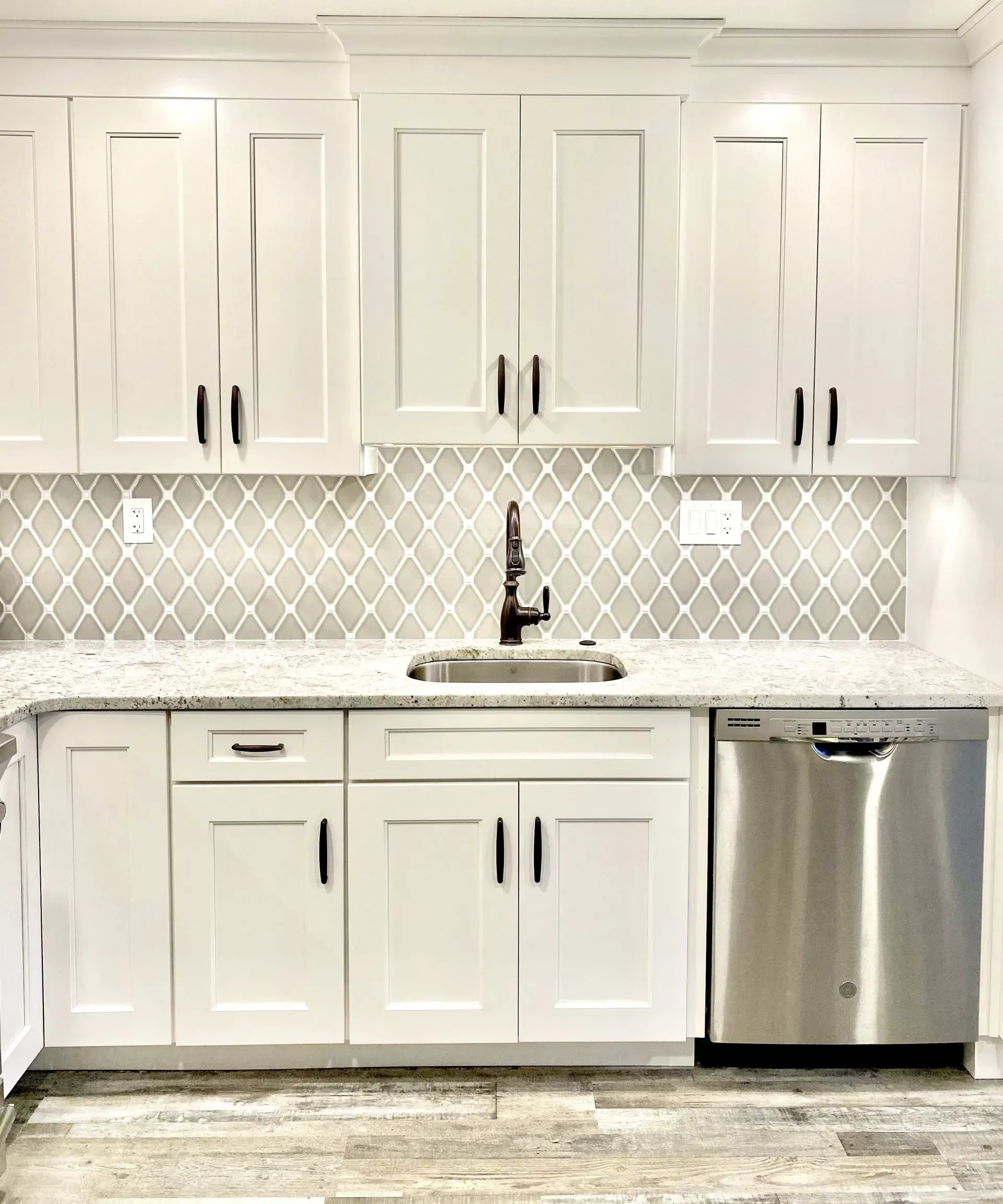 White kitchen with shaker cabinets, herringbone backsplash, sink, and stainless-steel dishwasher In Bucks Country PA